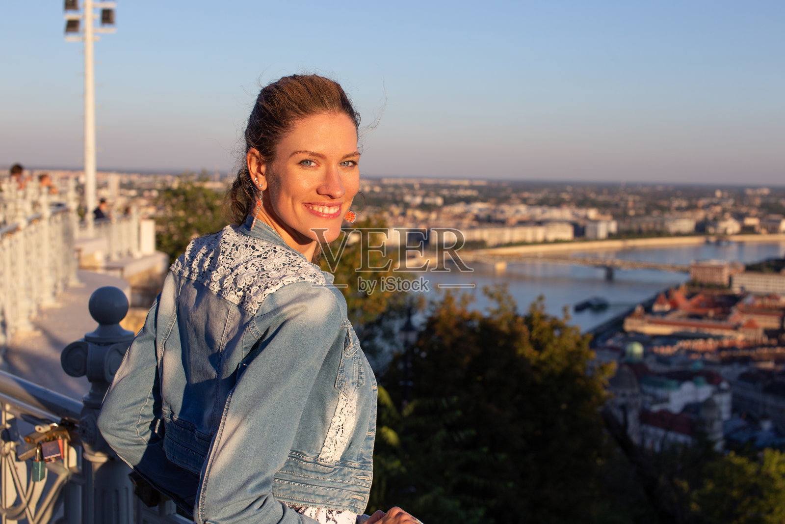 匈牙利布达佩斯，年轻的都市女子在夕阳中回望照片摄影图片