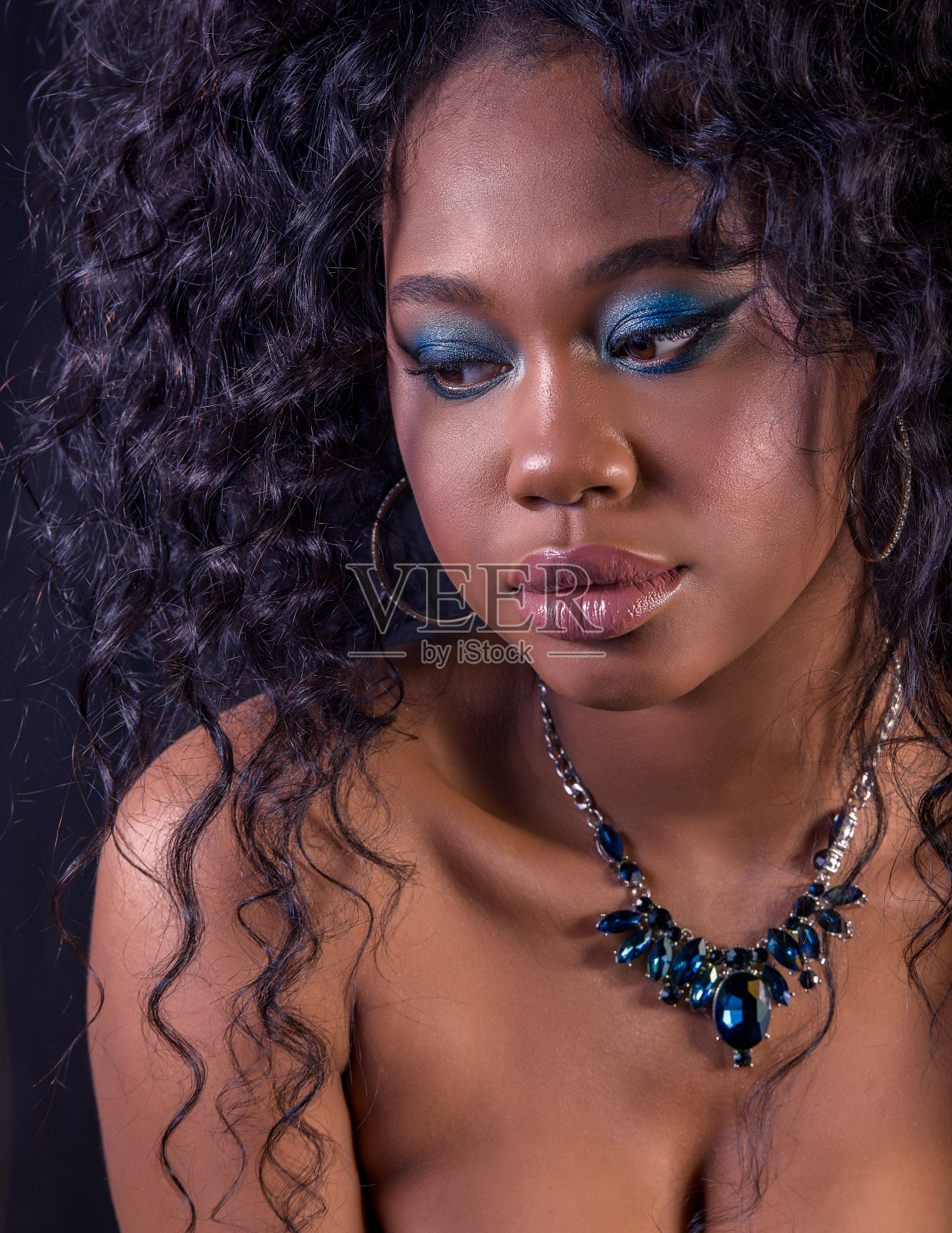 极端特写美丽的年轻非洲模特与卷曲的大头发，丰满的嘴唇和蓝色的化妆照片摄影图片