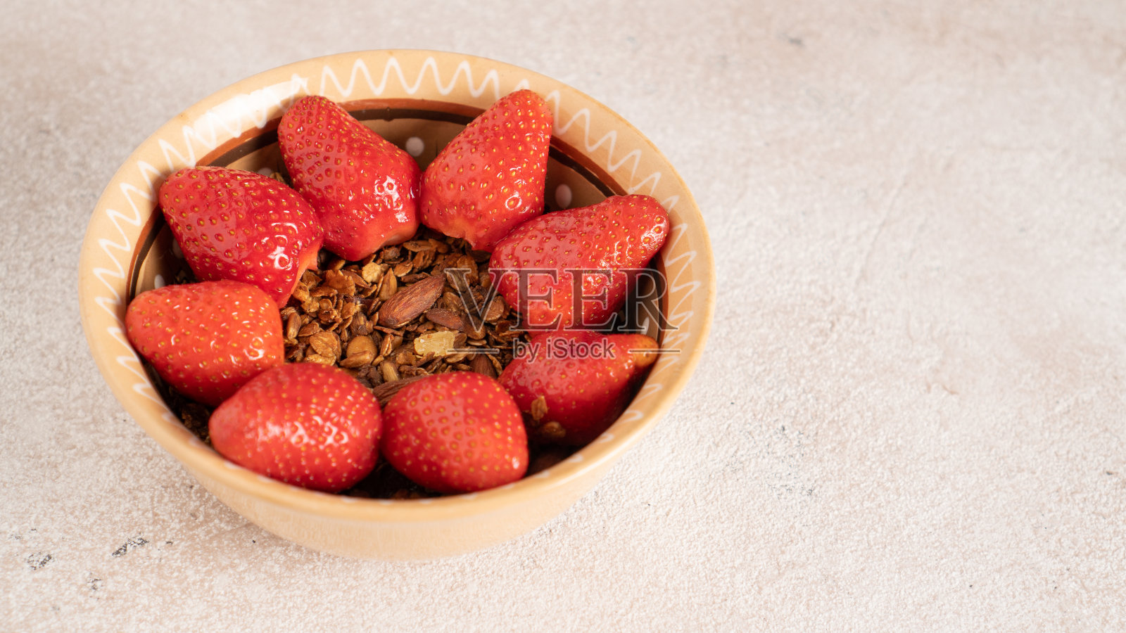 简单的早餐麦片碗和太阳形状的草莓。夏天的浆果和蜂蜜放在燕麦上面。甜的和健康的照片摄影图片