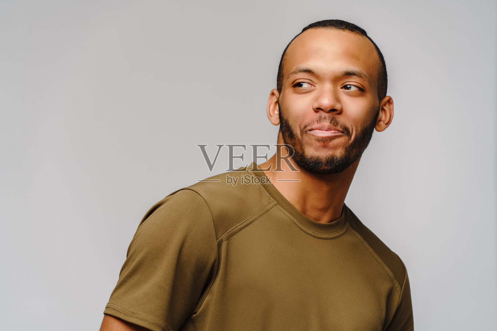 快乐友好的非洲裔美国年轻人在绿色t恤在浅灰色背景与拷贝空间照片摄影图片