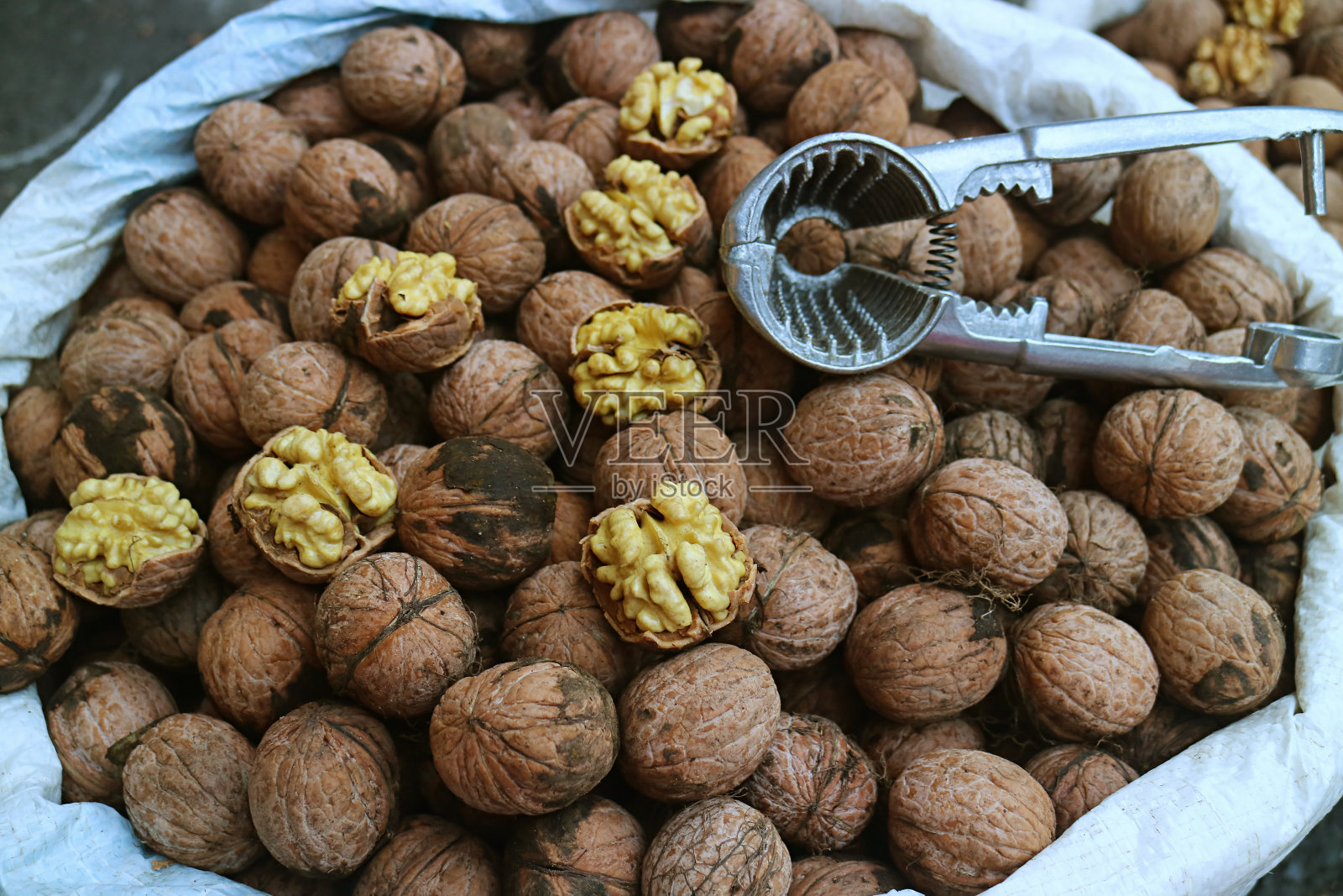 特写生核桃的核堆核桃与坚果壳和胡桃夹子工具照片摄影图片