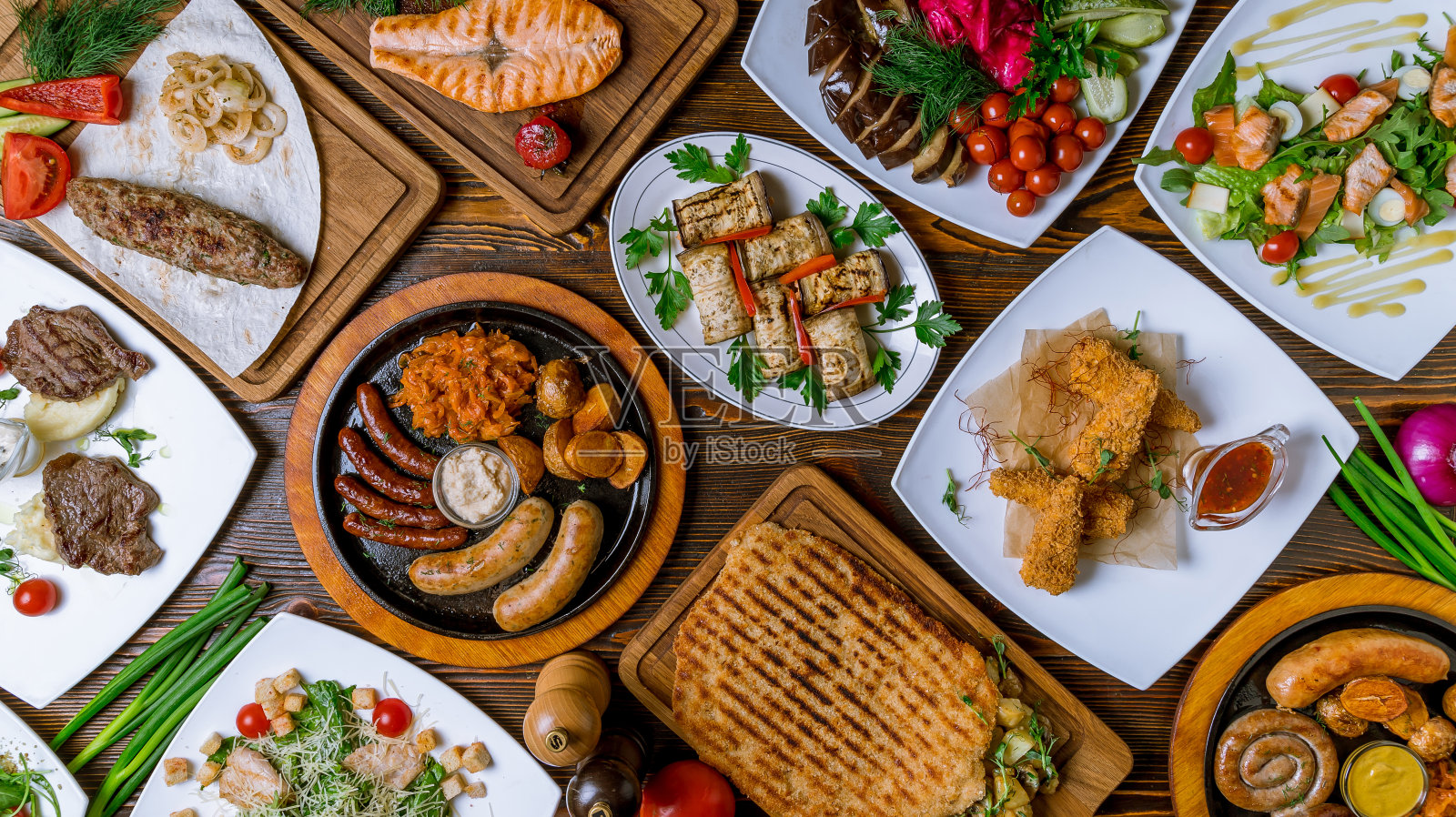 不同的膳食在桌面上的视图。什锦酱香肠，茄子卷，鲑鱼排，芝士棒，三文鱼沙拉，小牛肉维也纳炸肉排照片摄影图片