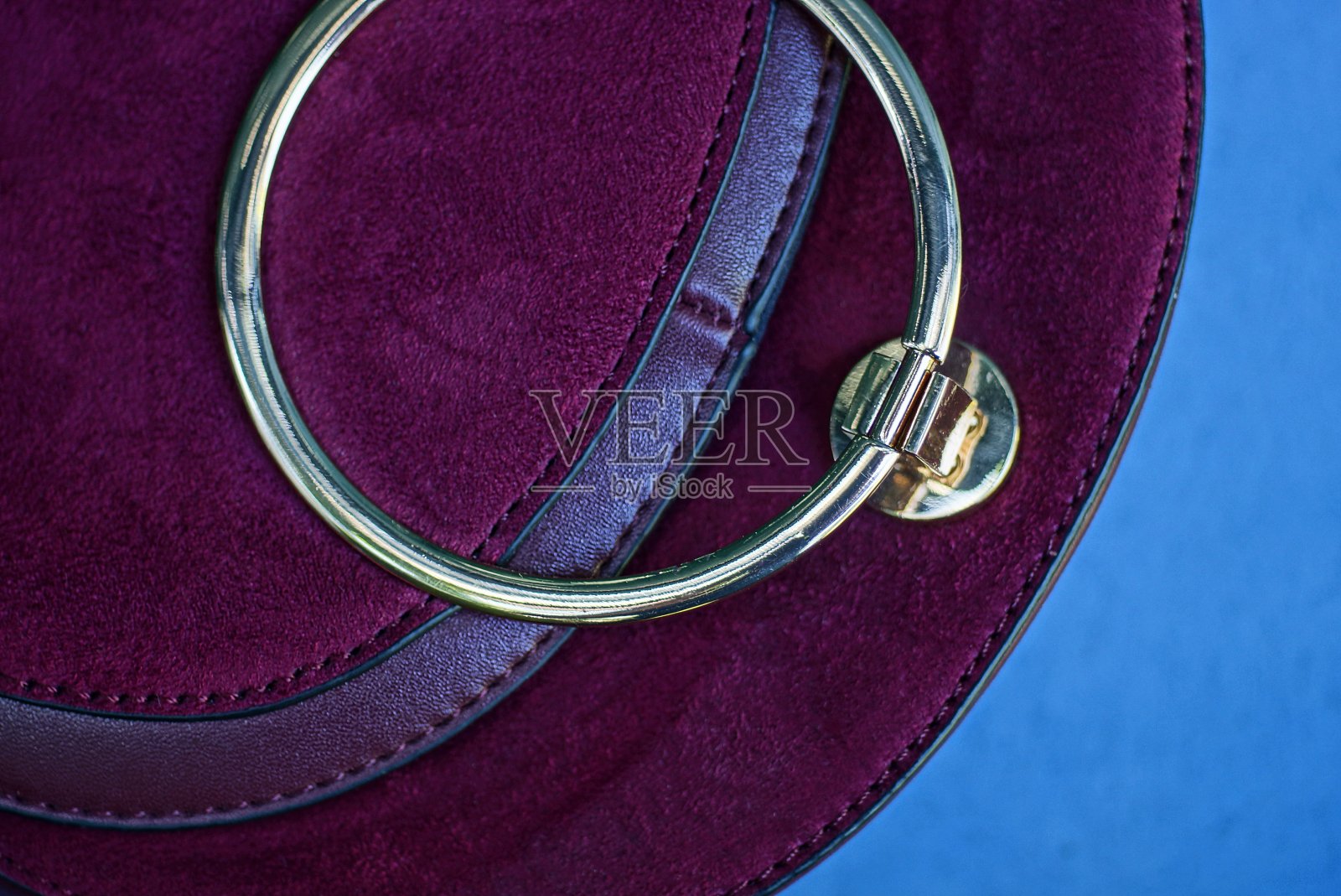 一个封闭的红色绒面革包的一部分，有一个黄色的圆形金属扣照片摄影图片