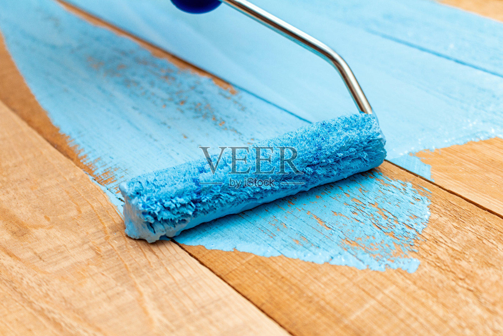 用油漆滚筒在绿色漆盘上画上蓝色的漆，在木制的背景上DIY照片摄影图片