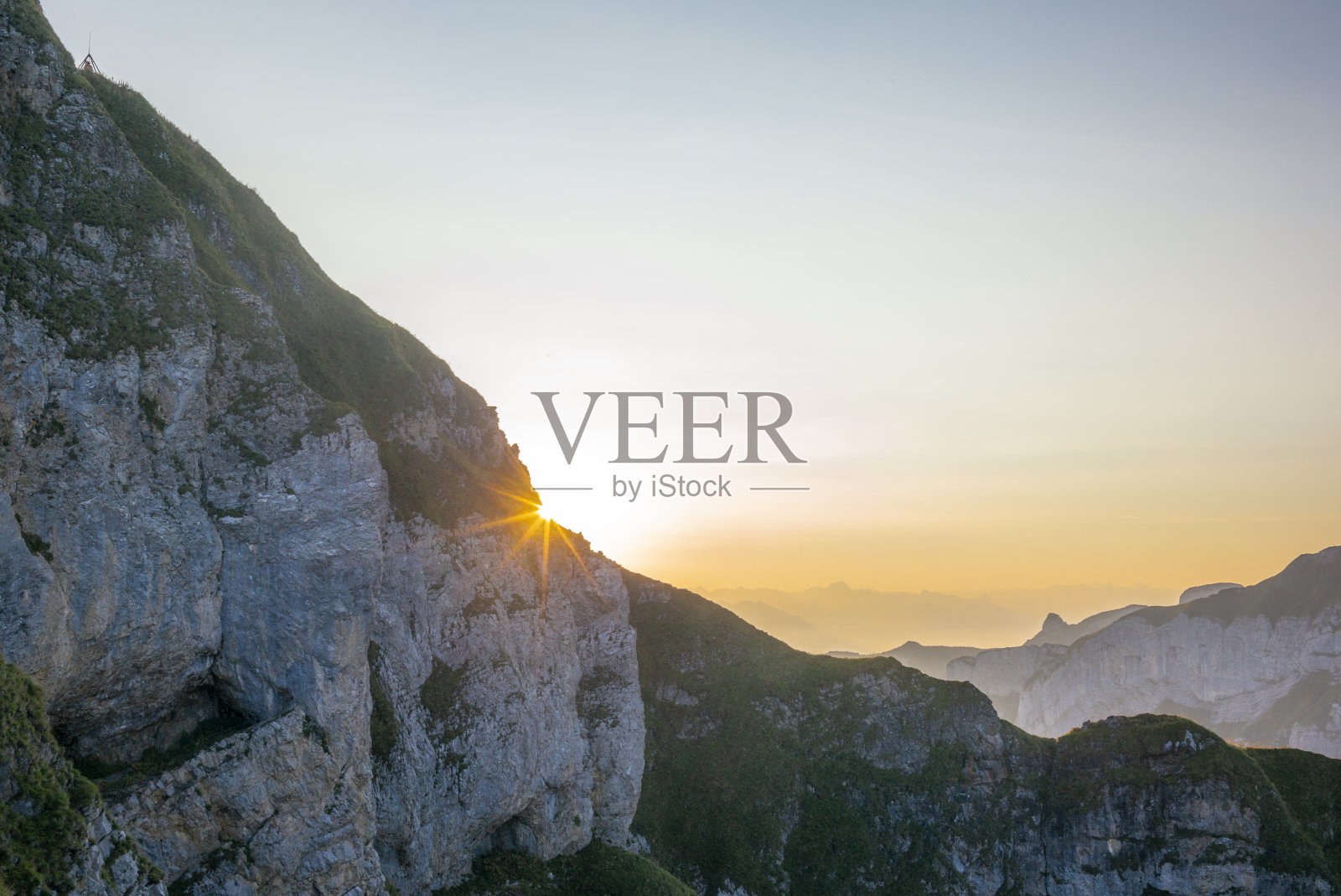 在瑞士阿彭策尔阿尔卑斯山脉的谢夫勒峰雄伟的云和陡峭的山脊上，五颜六色的日出和山谷中的雾翻滚在山上照片摄影图片