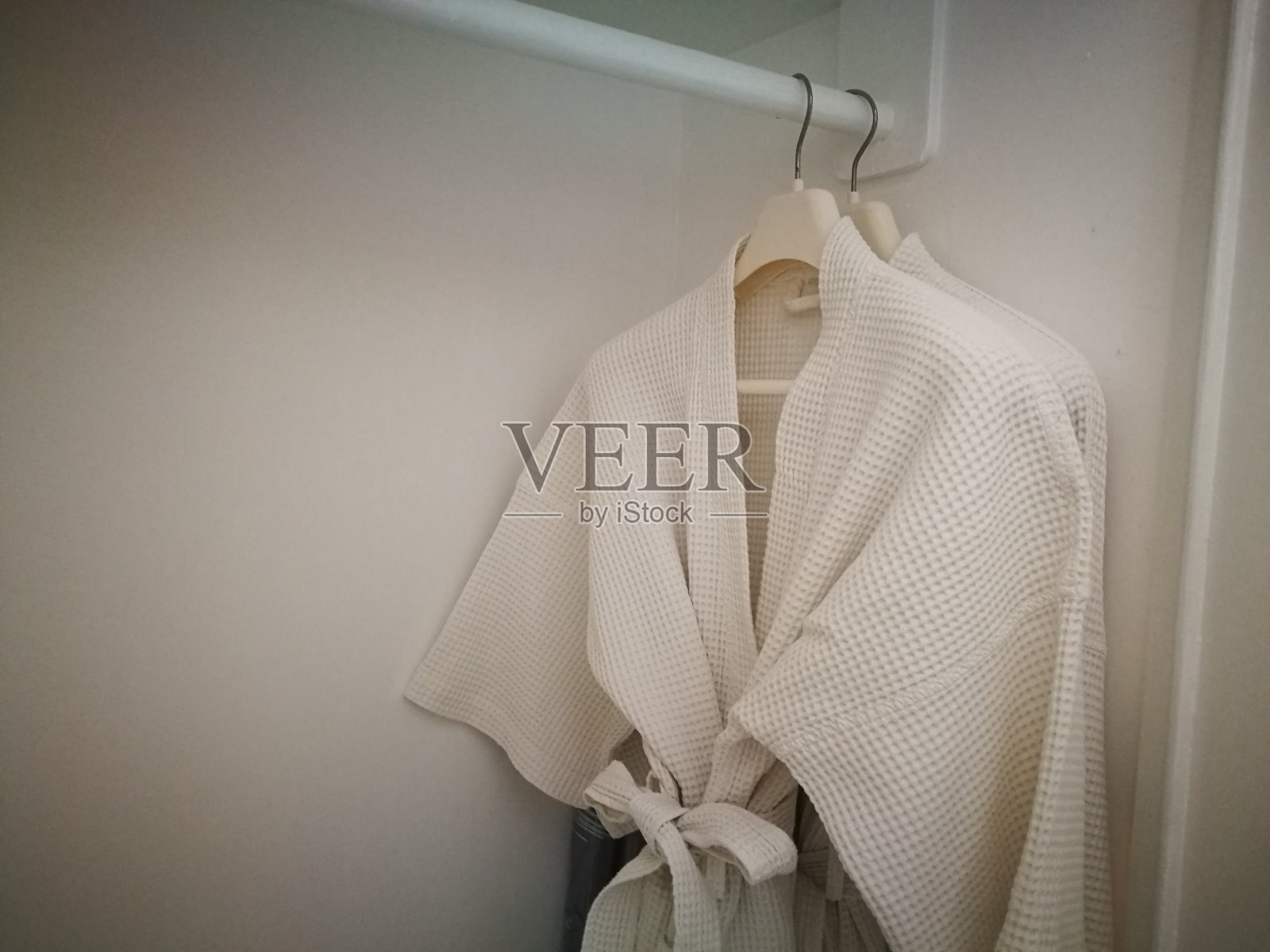 白色浴衣，浴巾挂在衣柜上。白色的斗篷。照片摄影图片