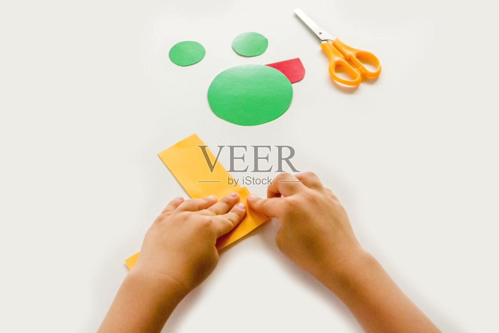 DIY的概念和孩子的创造力。一步步讲解:如何用纸制作贴花蛙。第三步孩子折纸。选择性聚焦，人工噪声，裁剪路径照片摄影图片