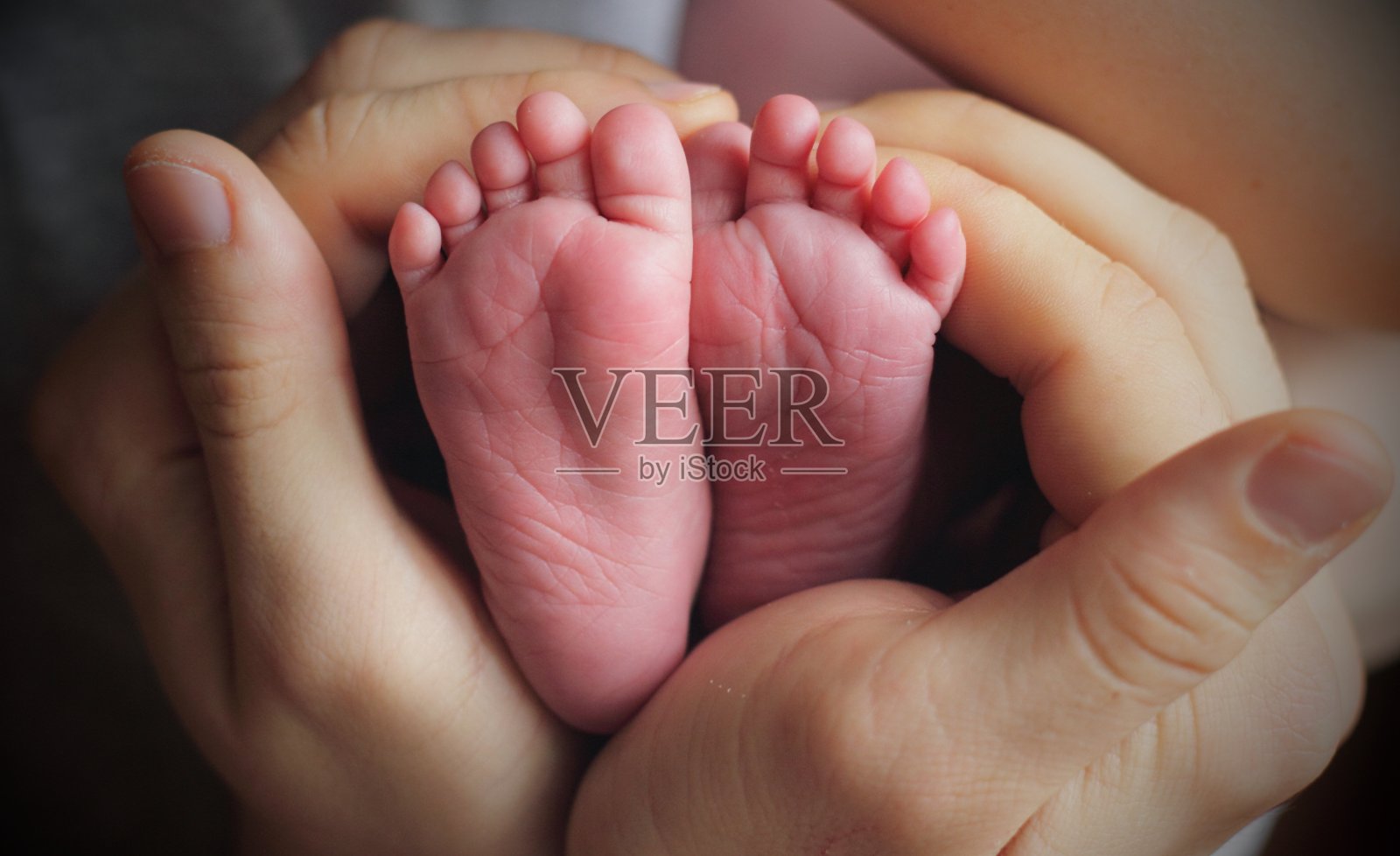 一个新生儿的脚在爸爸的关爱之手。心形的手掌照片摄影图片