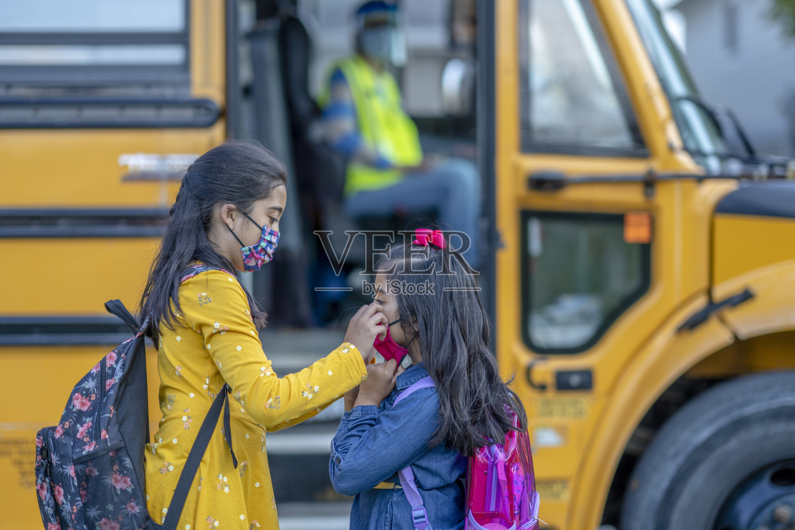 姐姐在上校车前调整好她的兄弟姐妹的口罩照片摄影图片