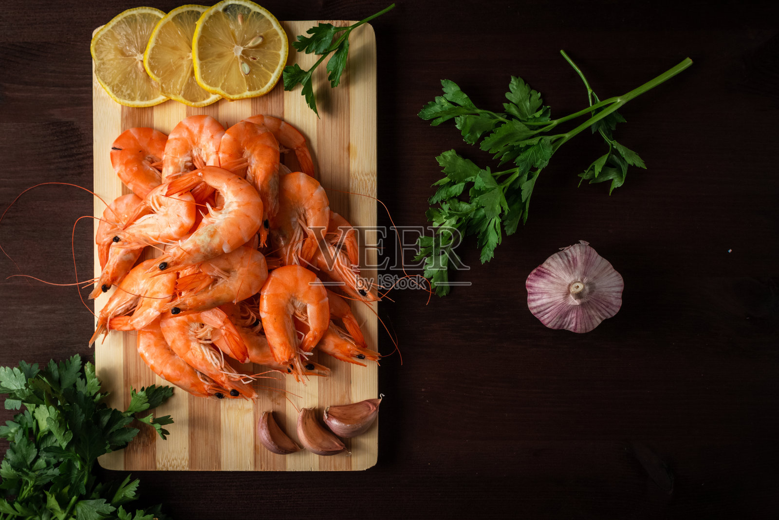 木桌上放着大虾、莳萝、欧芹和大蒜照片摄影图片