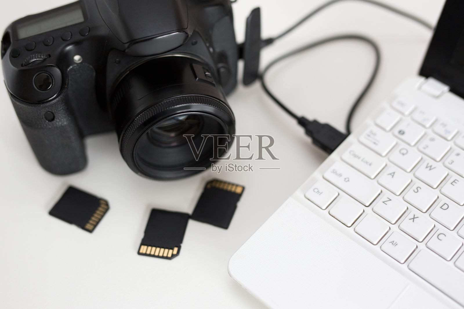 现代相机与电脑和存储卡连接在桌子上照片摄影图片