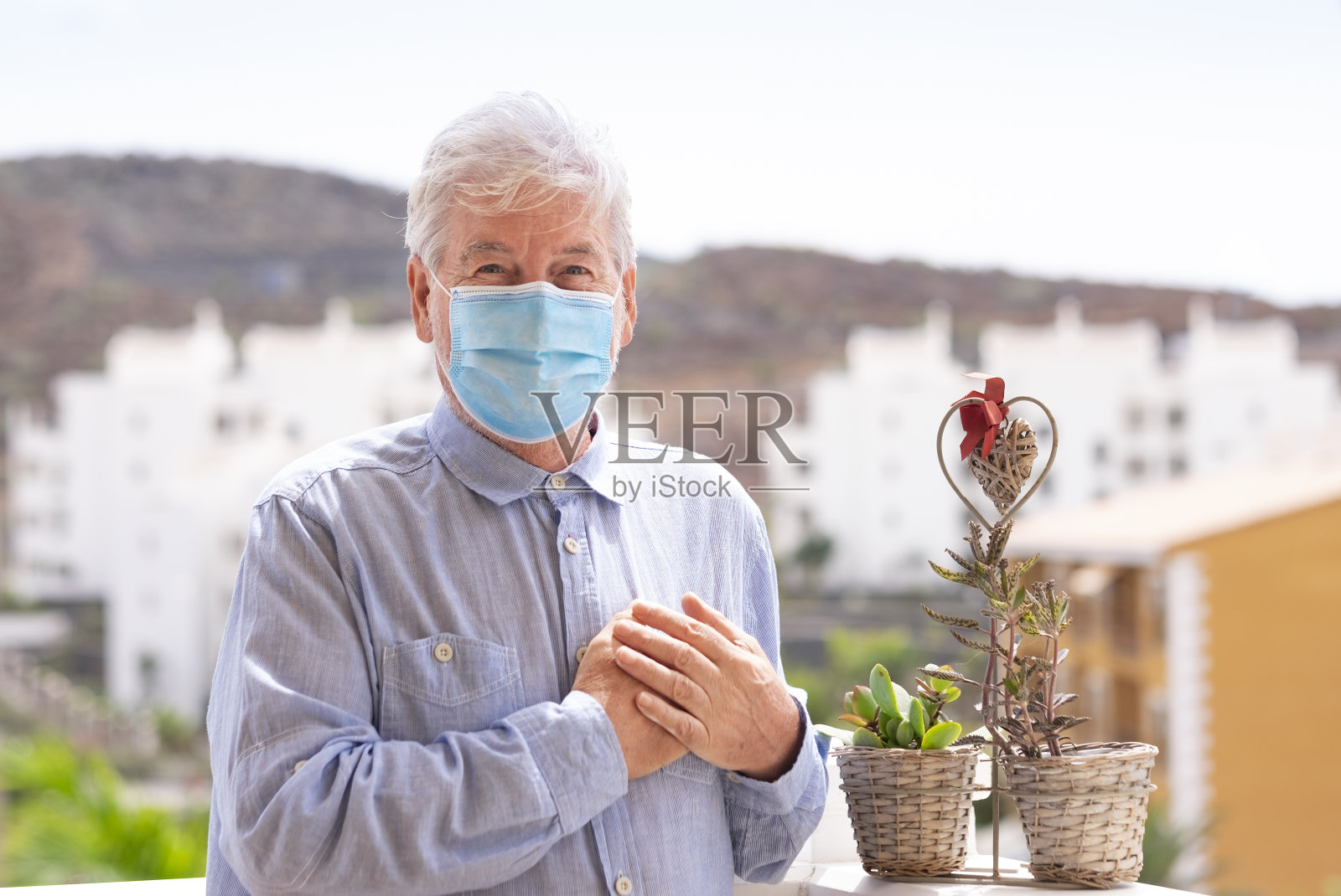 一位白发老人用手捂着胸口来问候。世界卫生组织针对新冠肺炎大流行推荐的新的问候方式照片摄影图片