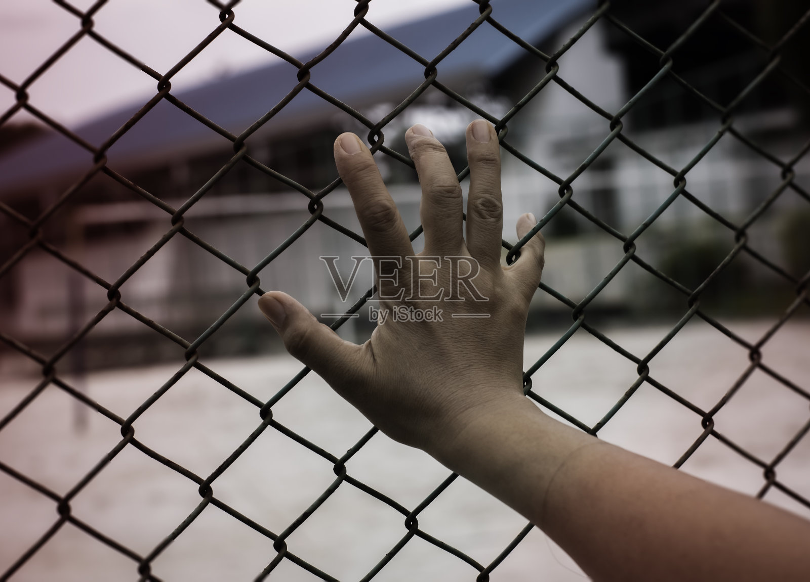 人的手碰在铁链栅栏上，四周光线模糊照片摄影图片