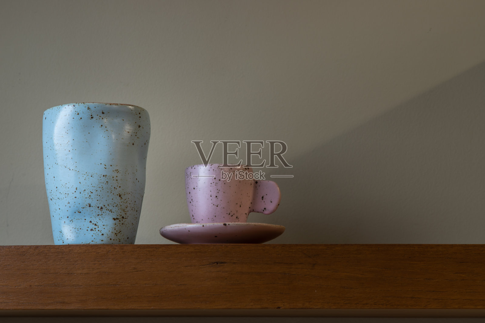 木制架子上手工制作的蓝色陶瓷马克杯。照片摄影图片