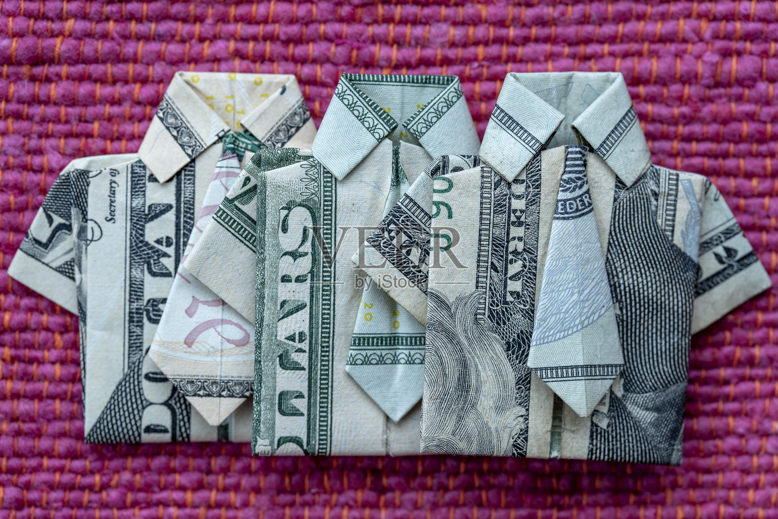 折纸衬衫的美元钞票上的红色织物背景。特写镜头。美元的t恤照片摄影图片