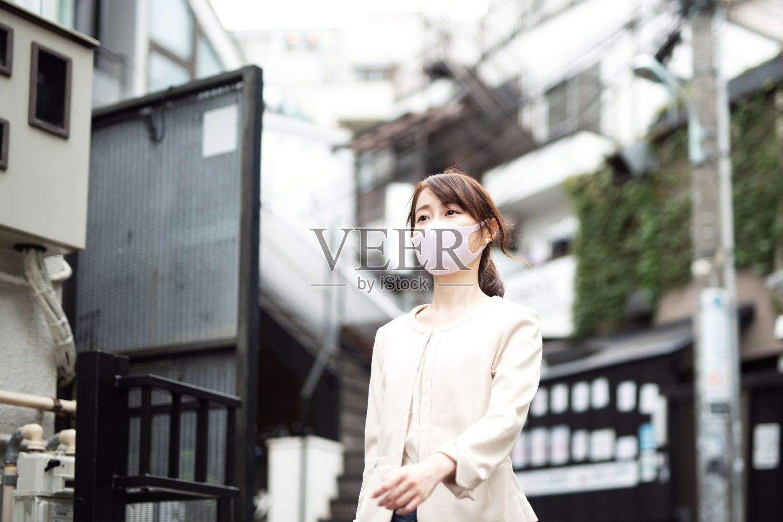 戴着面具的女商人走在住宅区的街道上照片摄影图片