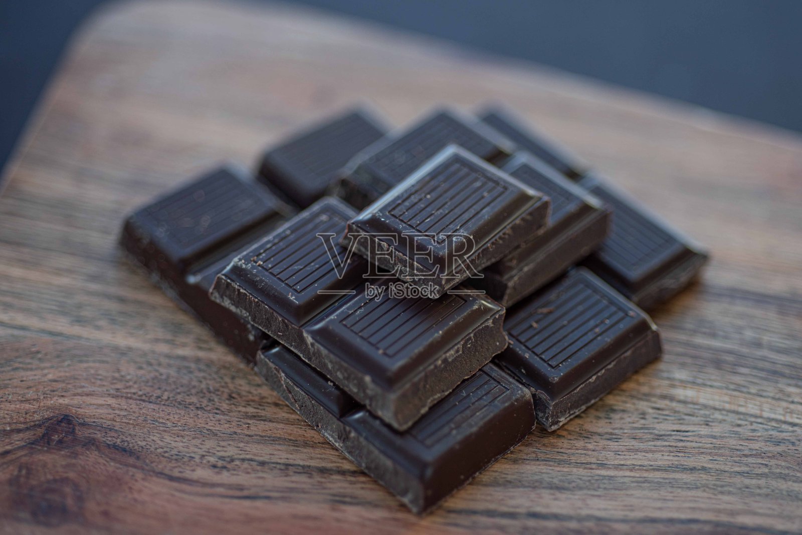 深色巧克力棒堆在木质表面上，背景模糊不清。照片摄影图片