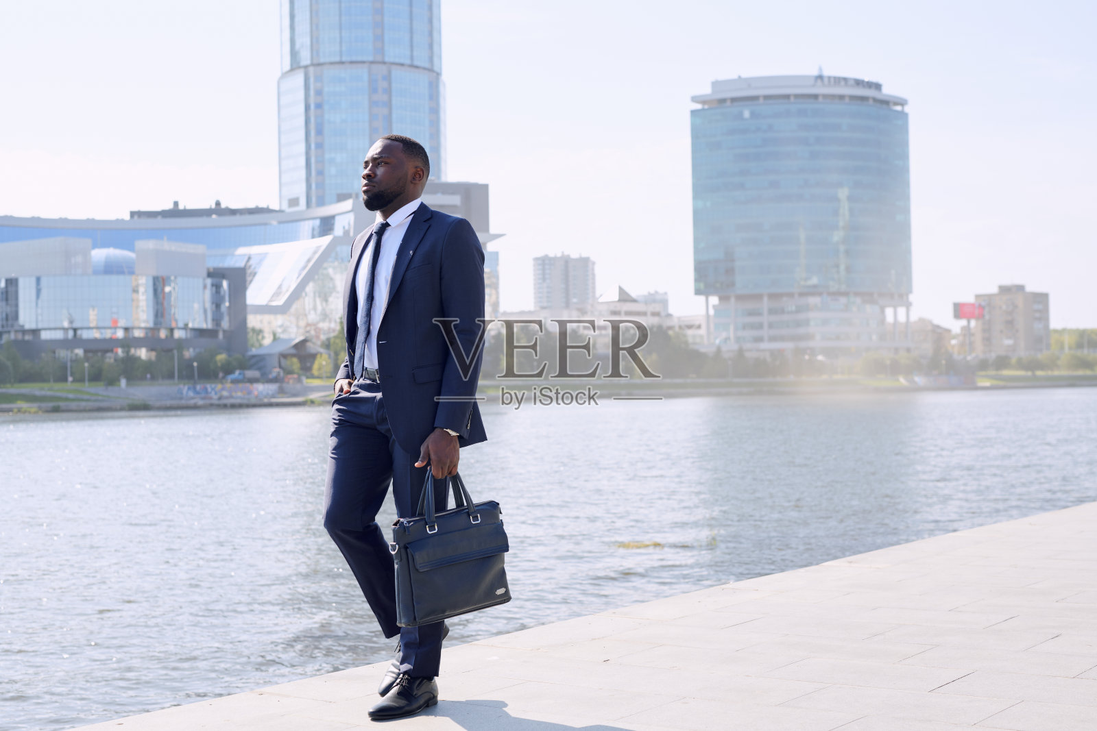 年轻的当代非洲商人穿着优雅的西装沿着河边行走照片摄影图片