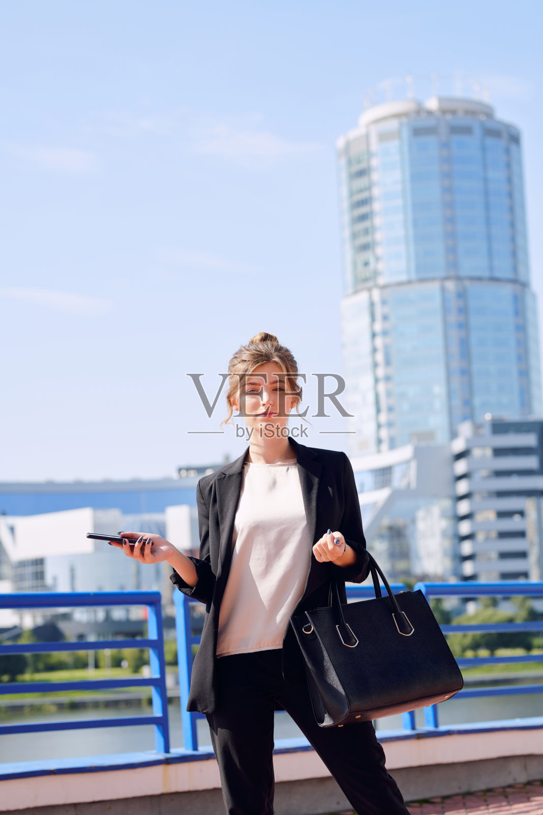 年轻的当代商业女性在智能休闲穿着手提袋和智能手机照片摄影图片