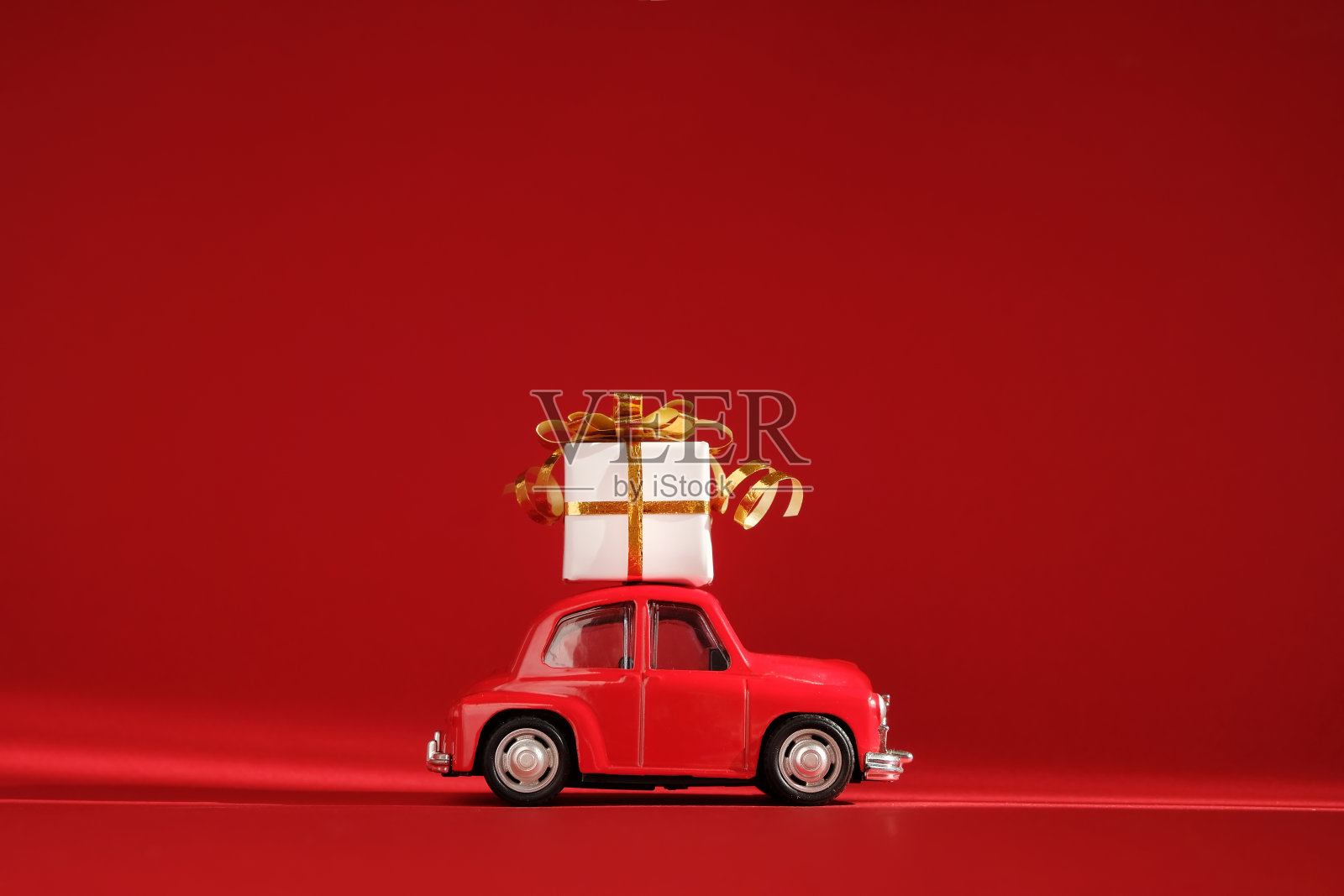 红色的红色背景上有礼物的红色复古小玩具车。交付。新年、圣诞节、情人节、世界妇女节、销售理念照片摄影图片