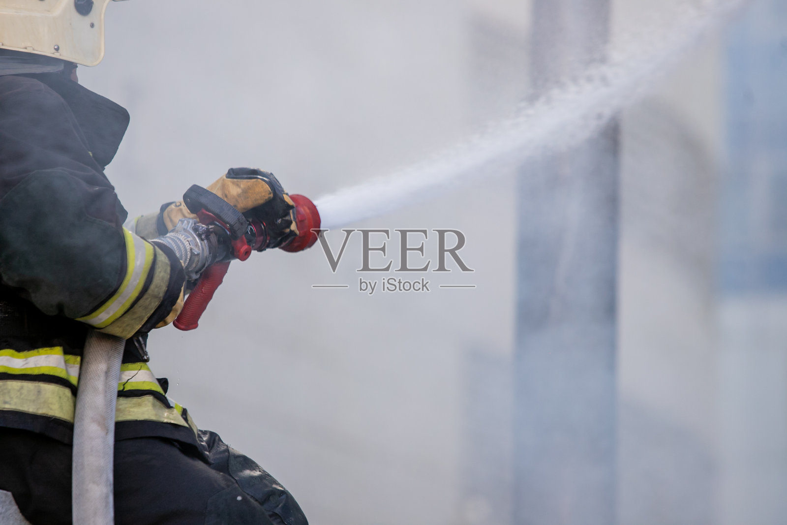 消防队员在消防训练中使用灭火器和水喉灭火。消防队员在危险情况下穿着消防服保护和安全。这支队伍属于公务员制度。照片摄影图片