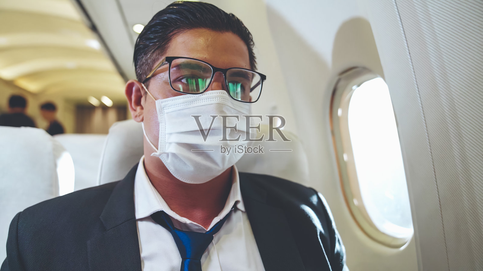 乘坐商务飞机时戴口罩的旅客。照片摄影图片