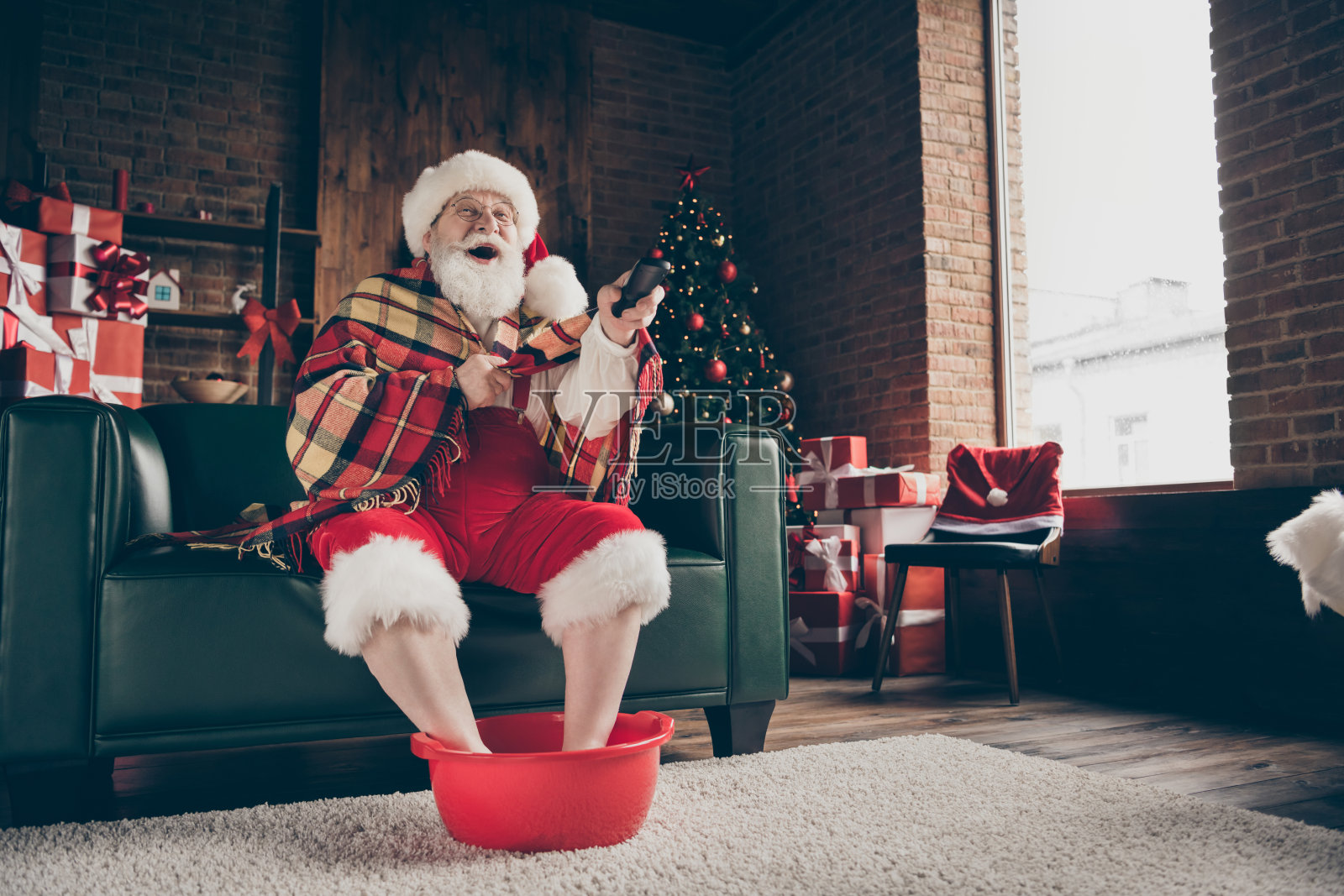 长照片白色的灰色的头发胡子圣诞老人坐在沙发放松圣诞礼物北方送看喜剧开关频道戴红帽子戴眼镜在房子在室内圣诞夜树照片摄影图片