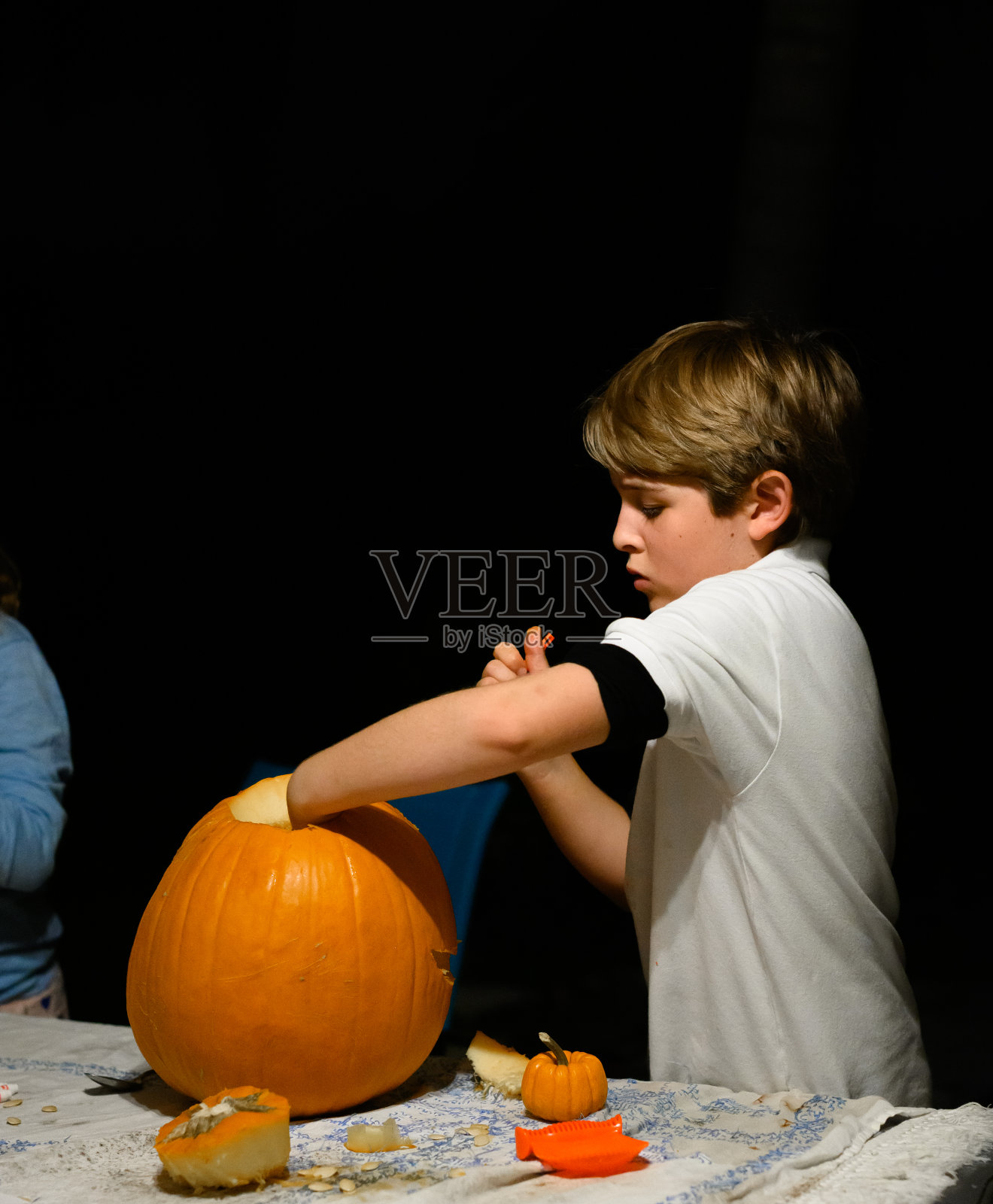男孩雕刻了一个万圣节南瓜照片摄影图片