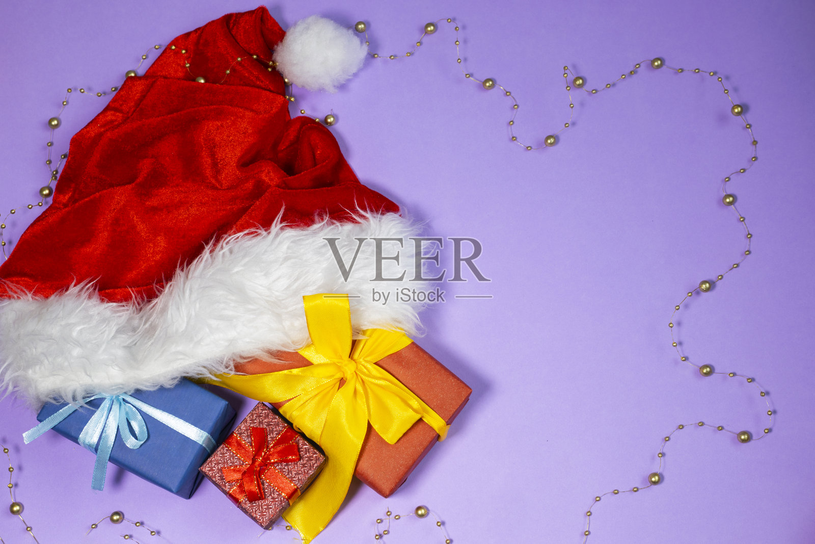 圣诞礼物和圣诞老人的帽子上五颜六色的背景。新年flatlay。照片摄影图片
