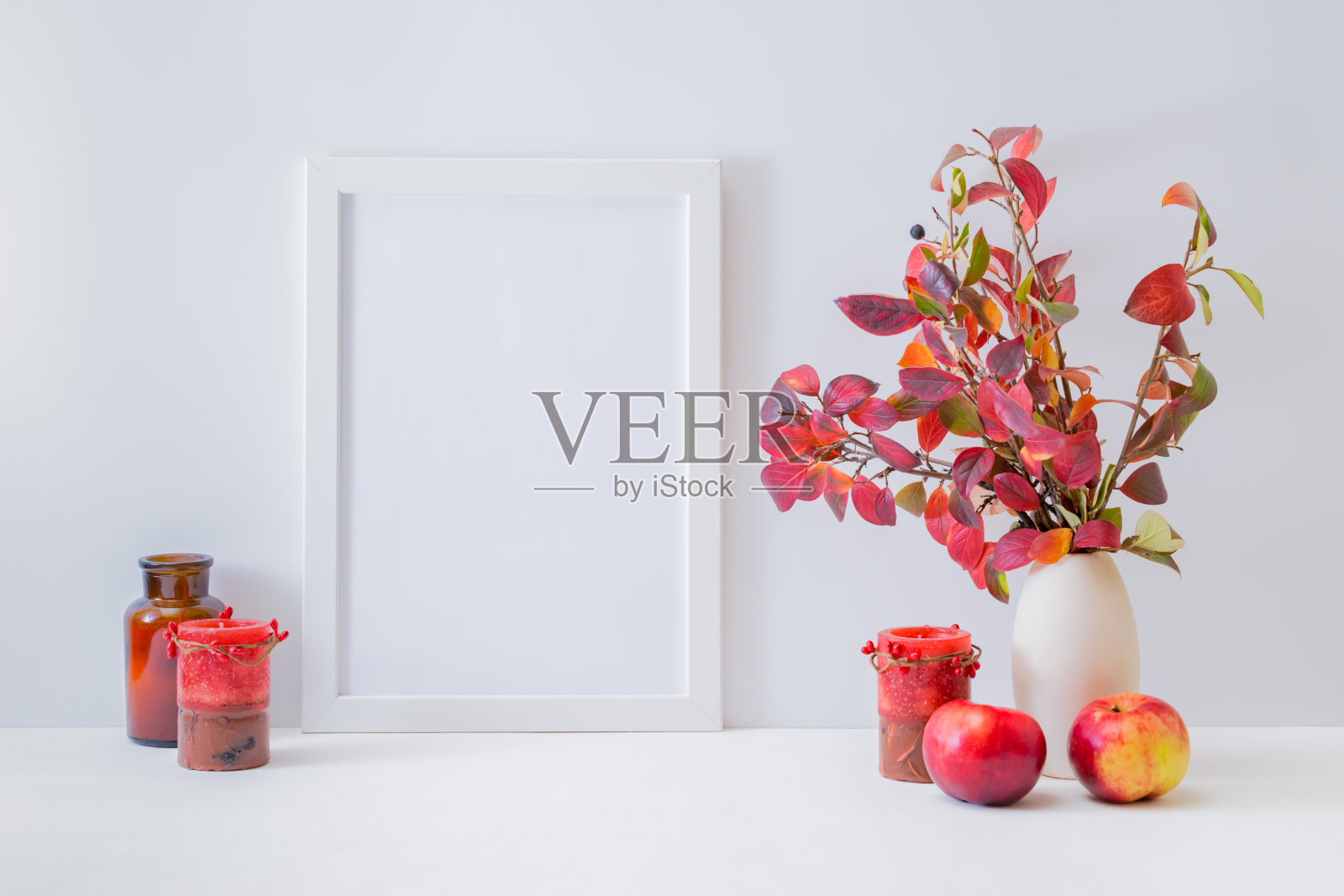 家庭内部装饰元素。模型与白色框架，彩色秋天的叶子在一个花瓶上的一个轻的背景照片摄影图片