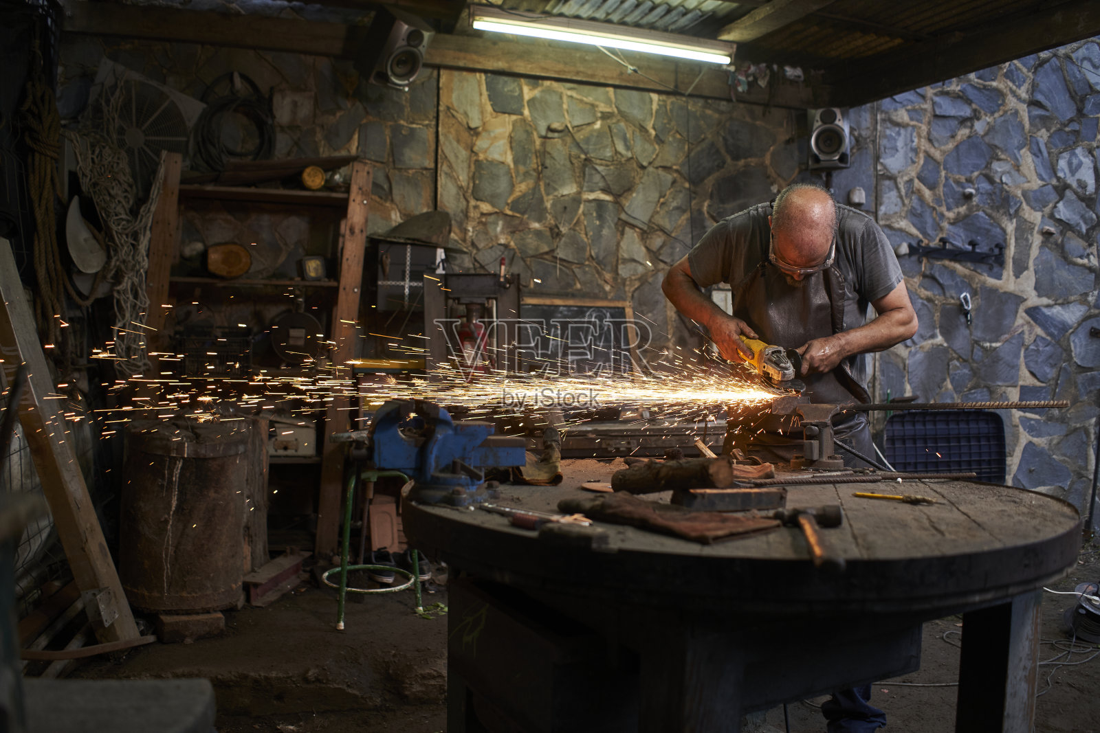 工人在旧的铁匠店里用磨床切割。照片摄影图片