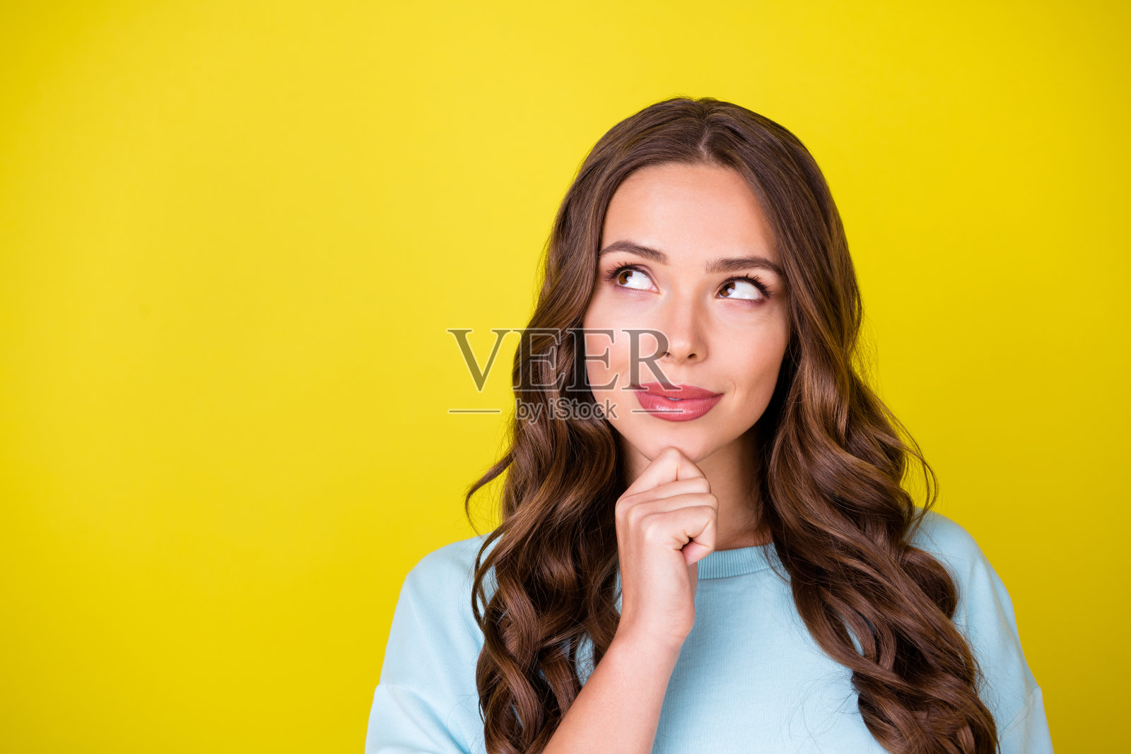 可爱的梦幻的年轻女孩的照片手下巴微笑想象看复制空间做出选择看到有前途的机会穿蓝色套衫孤立亮黄色背景照片摄影图片