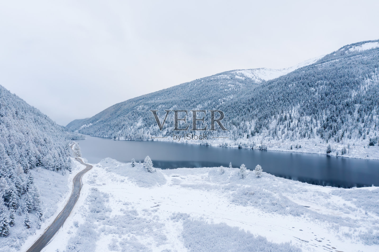 秋天的第一场雪覆盖了山谷和湖的倒影和道路照片摄影图片