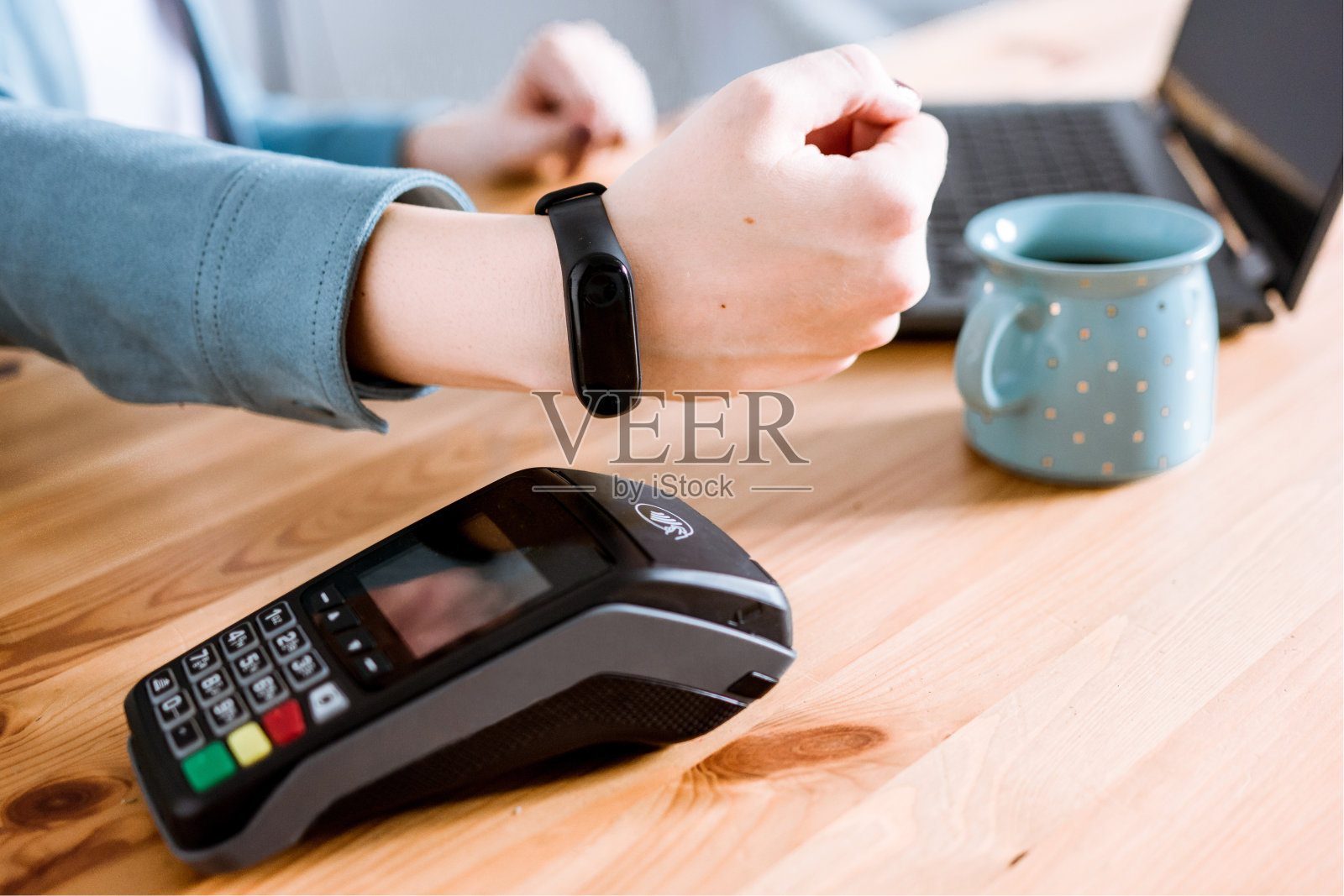 一名女子在咖啡馆通过智能手表使用POS终端进行非接触式支付。NFC支付新技术照片摄影图片