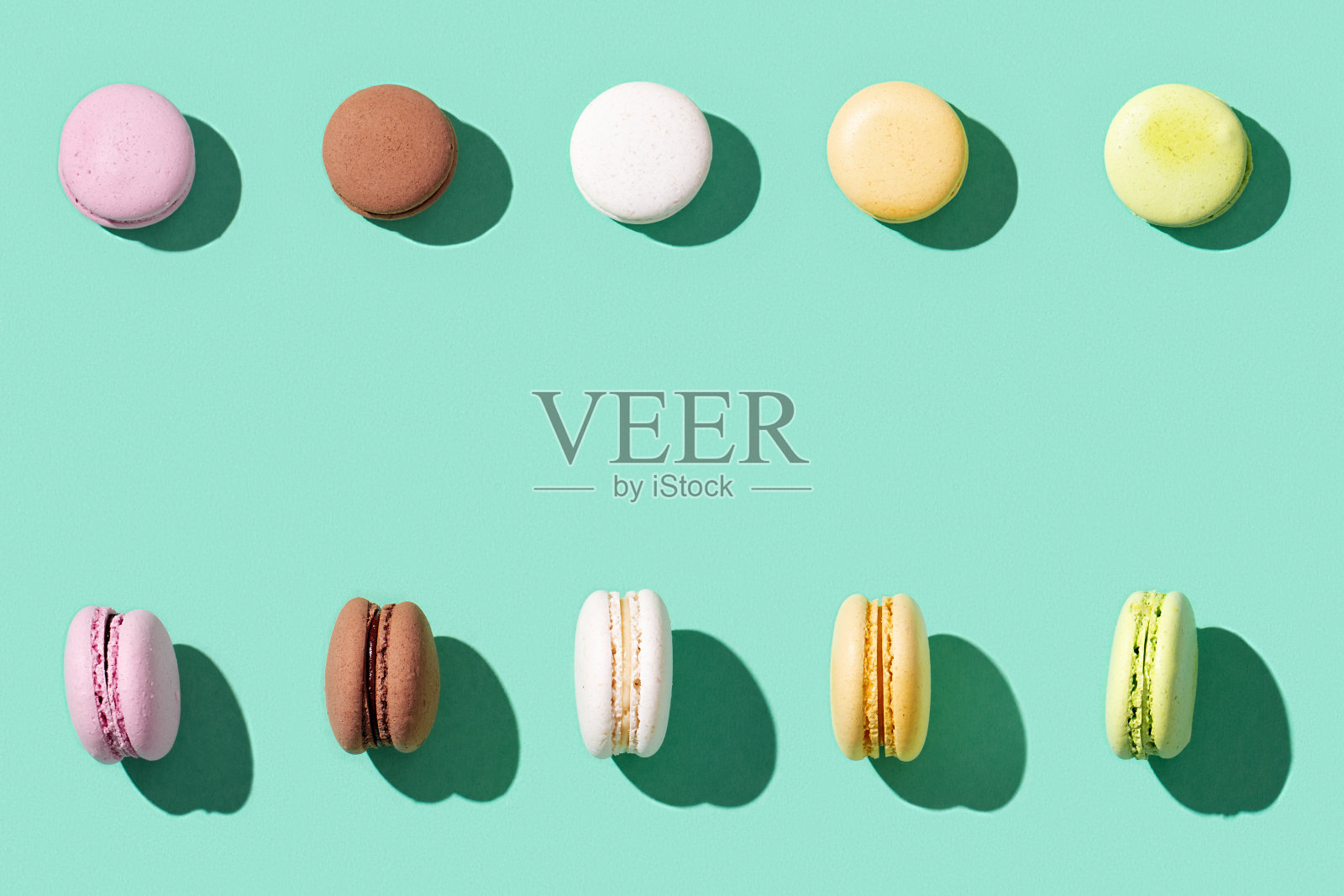 亮蓝绿色背景的什锦马卡龙，五颜六色的法式曲奇马卡龙。照片摄影图片