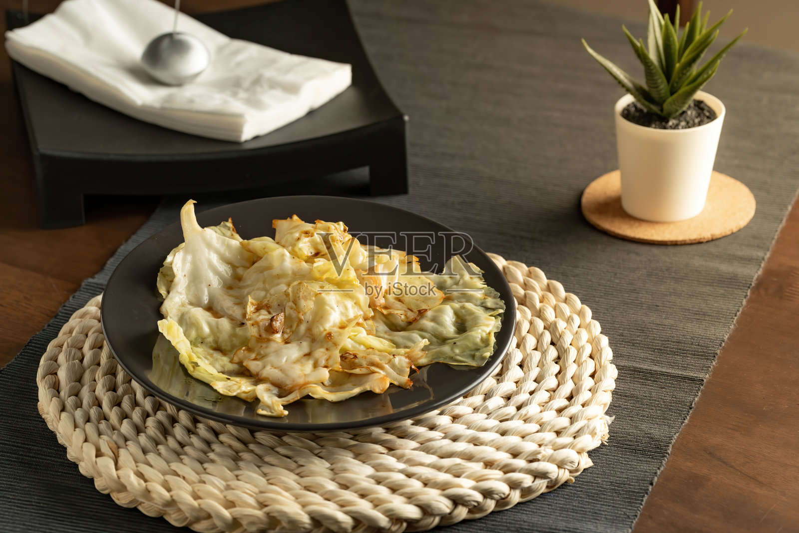 美味多汁，炒白菜与鱼酱在一个黑色的盘子，并装饰桌子与餐巾架和植物。照片摄影图片