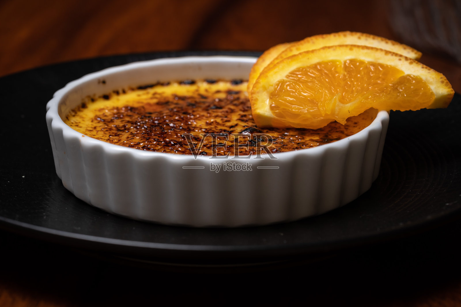 深色木桌上有焦糖，焦奶油和橙色。照片摄影图片