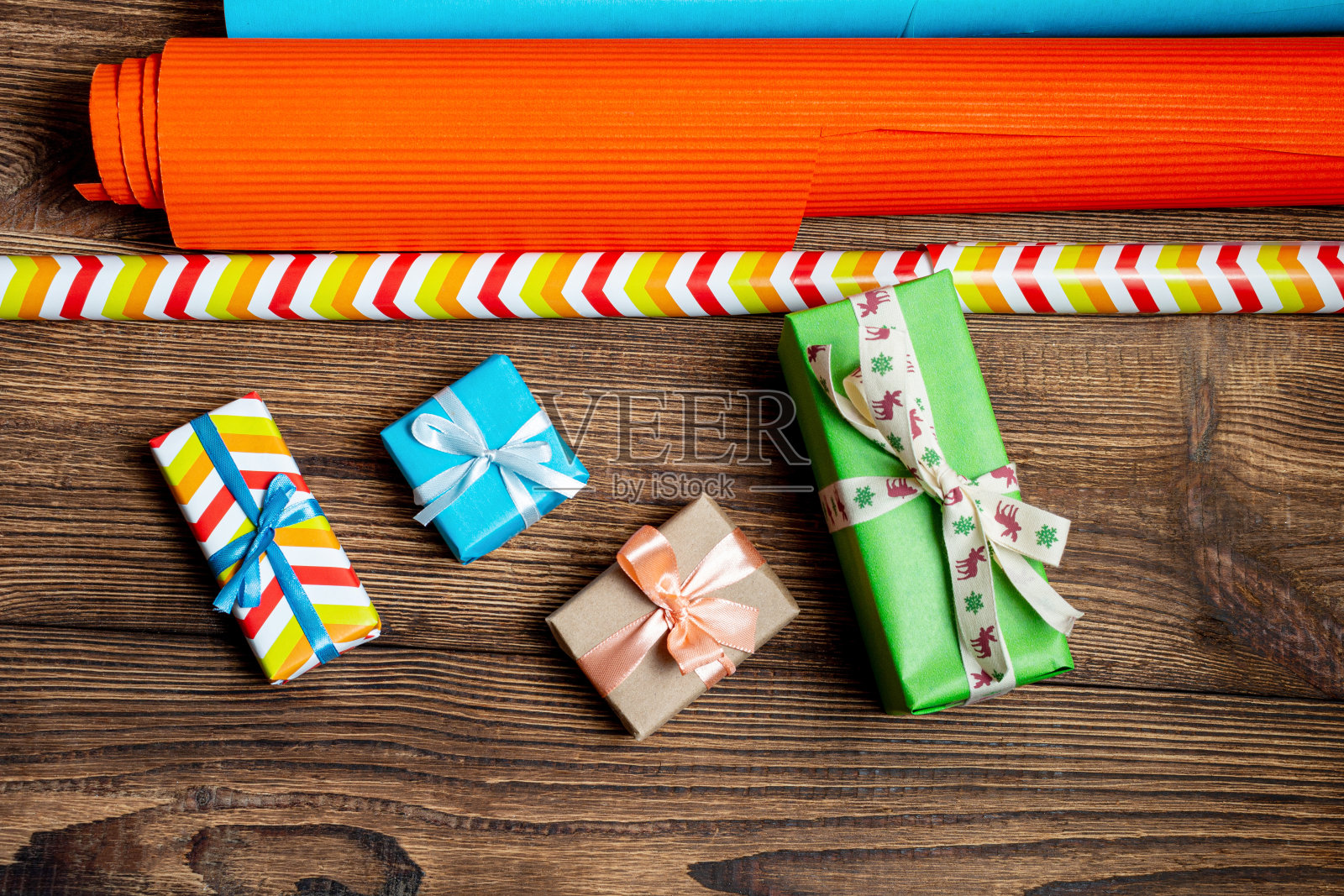 礼品盒和彩色包装纸上的木制棕色背景。为新年和圣诞节做准备的概念。照片摄影图片