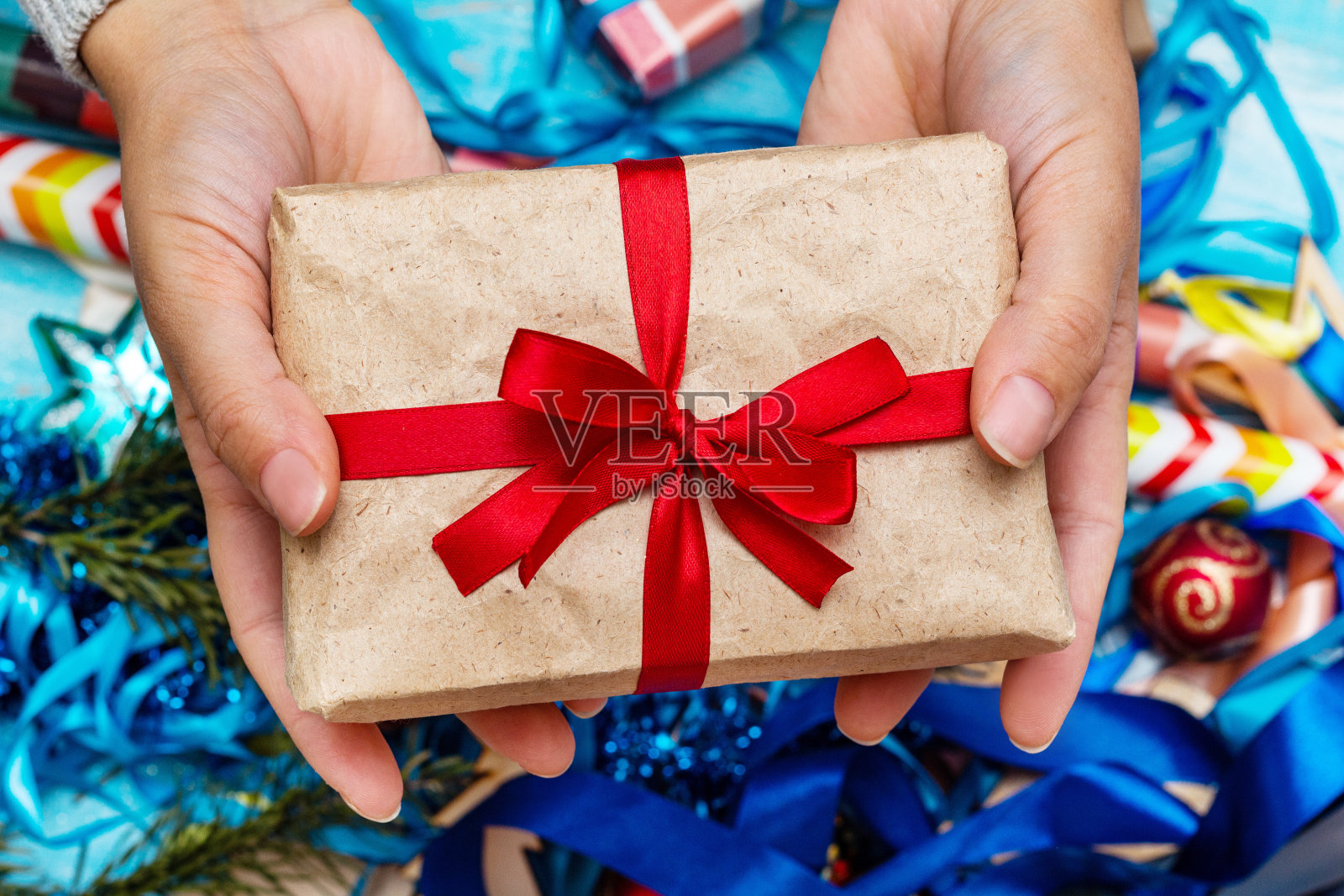 手在一个针织毛衣持有礼品盒。圣诞假期准备概念。照片摄影图片