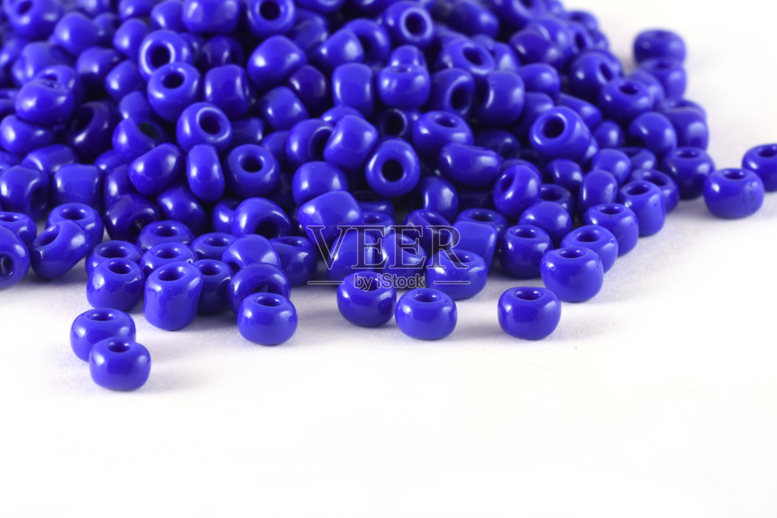 白色背景上的蓝色珠子的特写。珠子的背景或纹理。宏，用于时装服装的整理。为时尚女性制作珠子项链或串珠。照片摄影图片