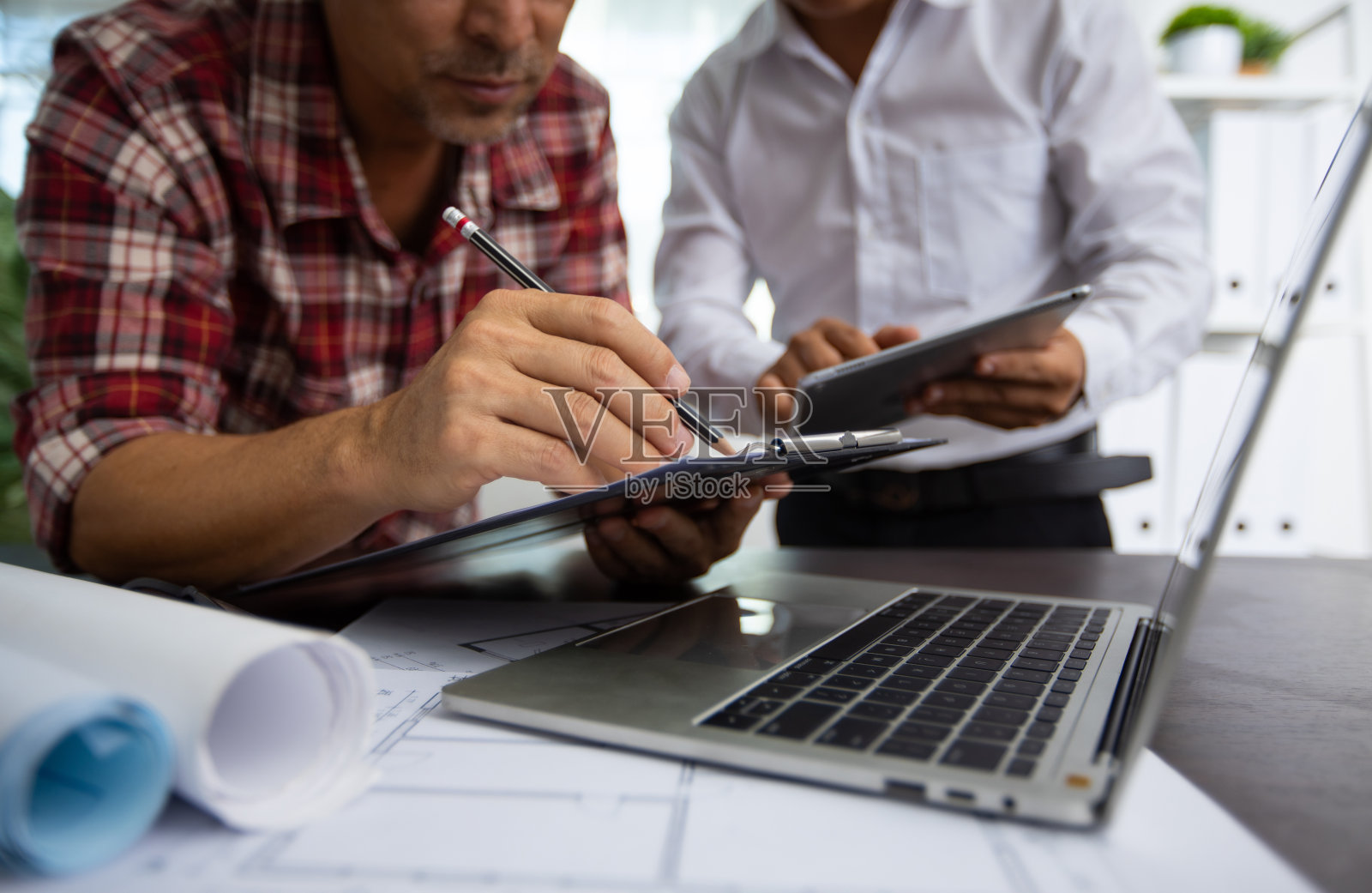 工程师在平板上详细讲解项目工作，与合作伙伴一起讨论图纸，在纸上写数据，建筑师会议，设计师头脑风暴和团队理念照片摄影图片