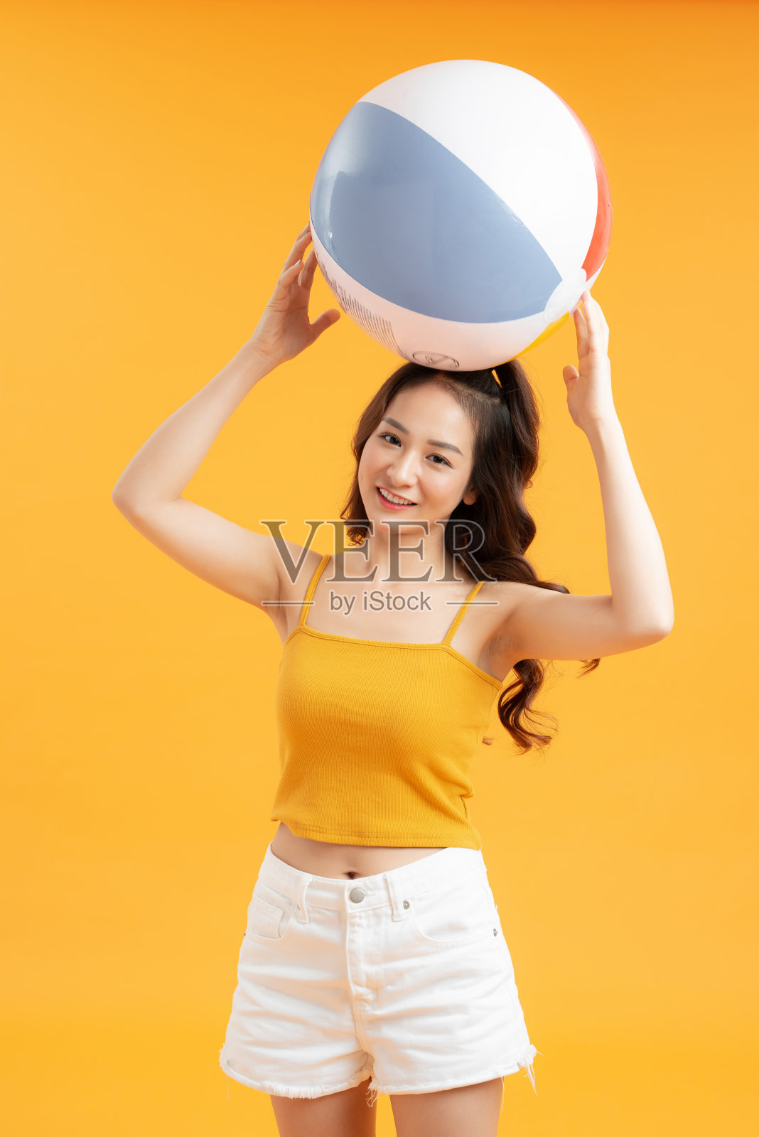 漂亮的女孩与沙滩球，孤立在黄色的背景照片摄影图片