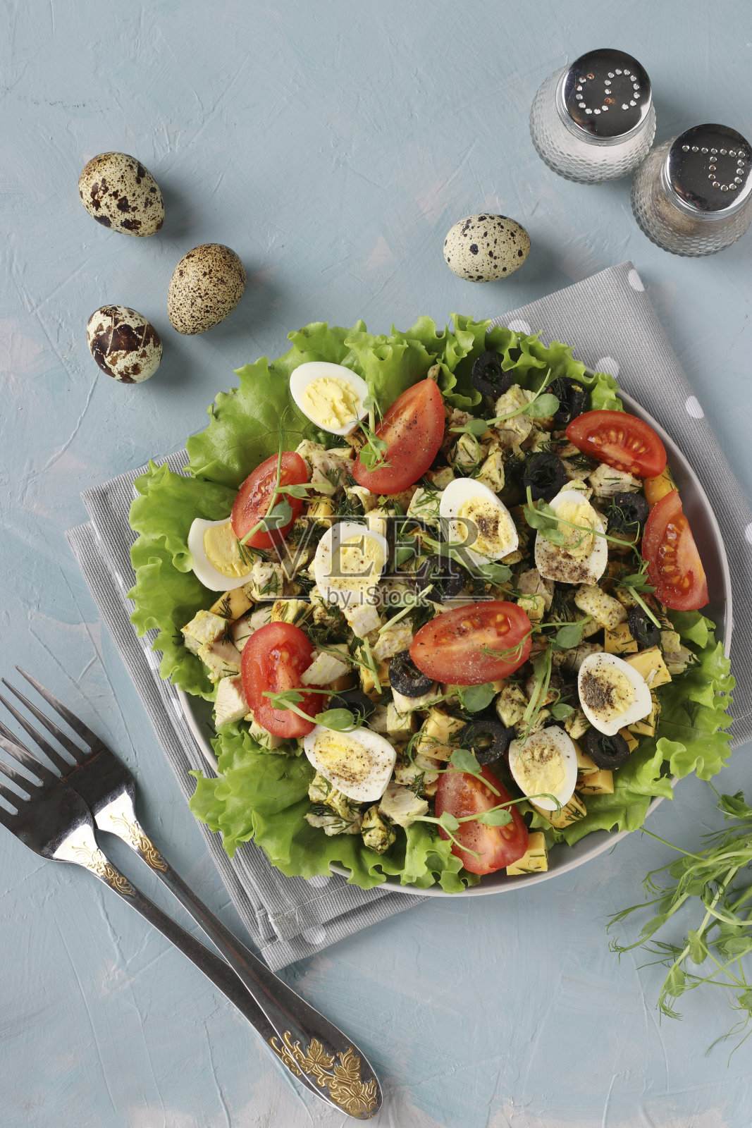 有机沙拉，鸡肉，樱桃番茄，鹌鹑蛋，黑橄榄和微绿色在浅蓝色的背景，健康饮食日，俯视图，垂直格式照片摄影图片