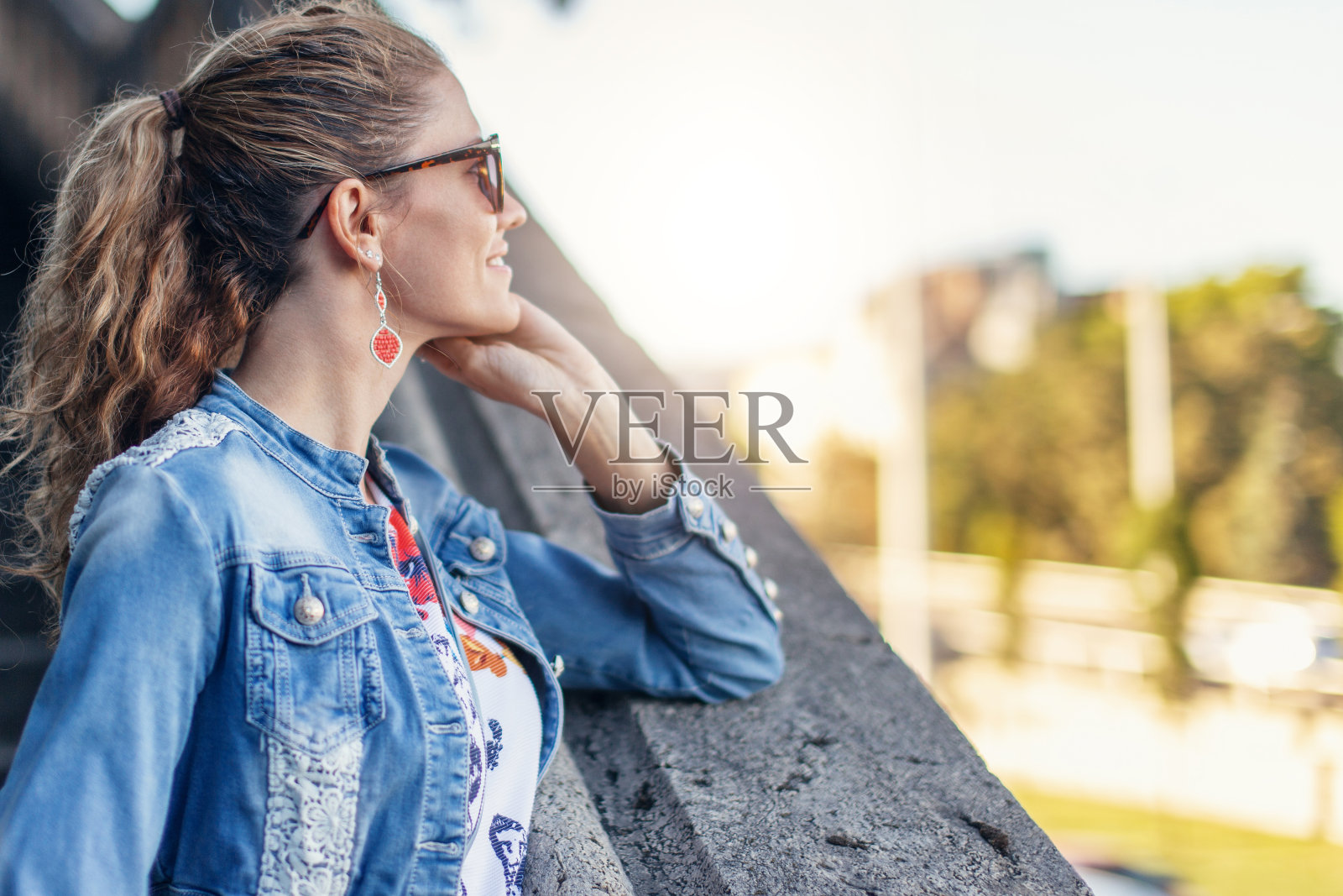 穿着牛仔夹克的年轻女子在秋天看向别处的公园照片摄影图片