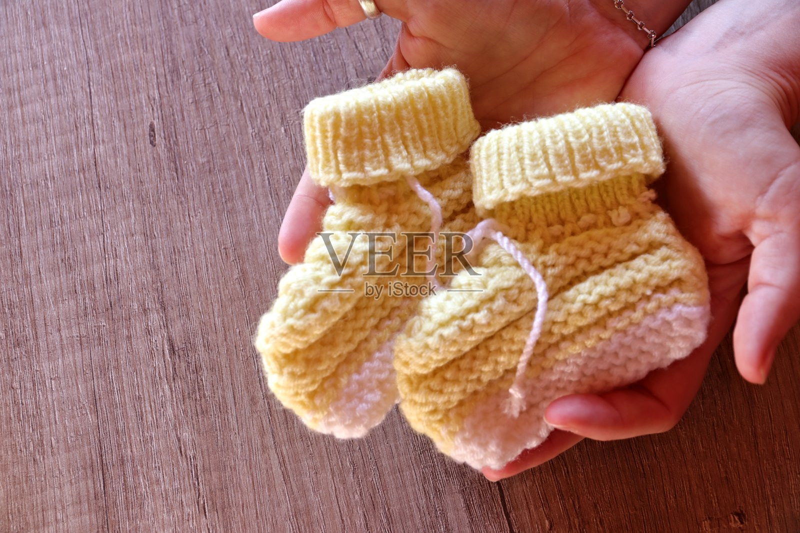 拿着自己制作的针织婴儿靴照片摄影图片