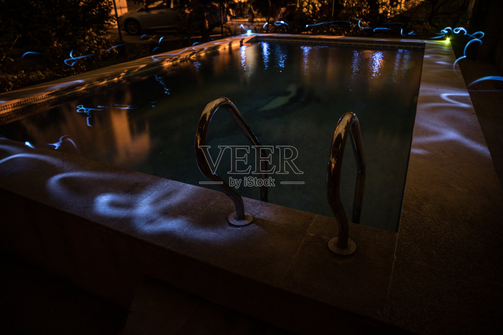 游泳池和瀑布在夜间度假的背景。彩色光装饰。Freezelight照片摄影图片