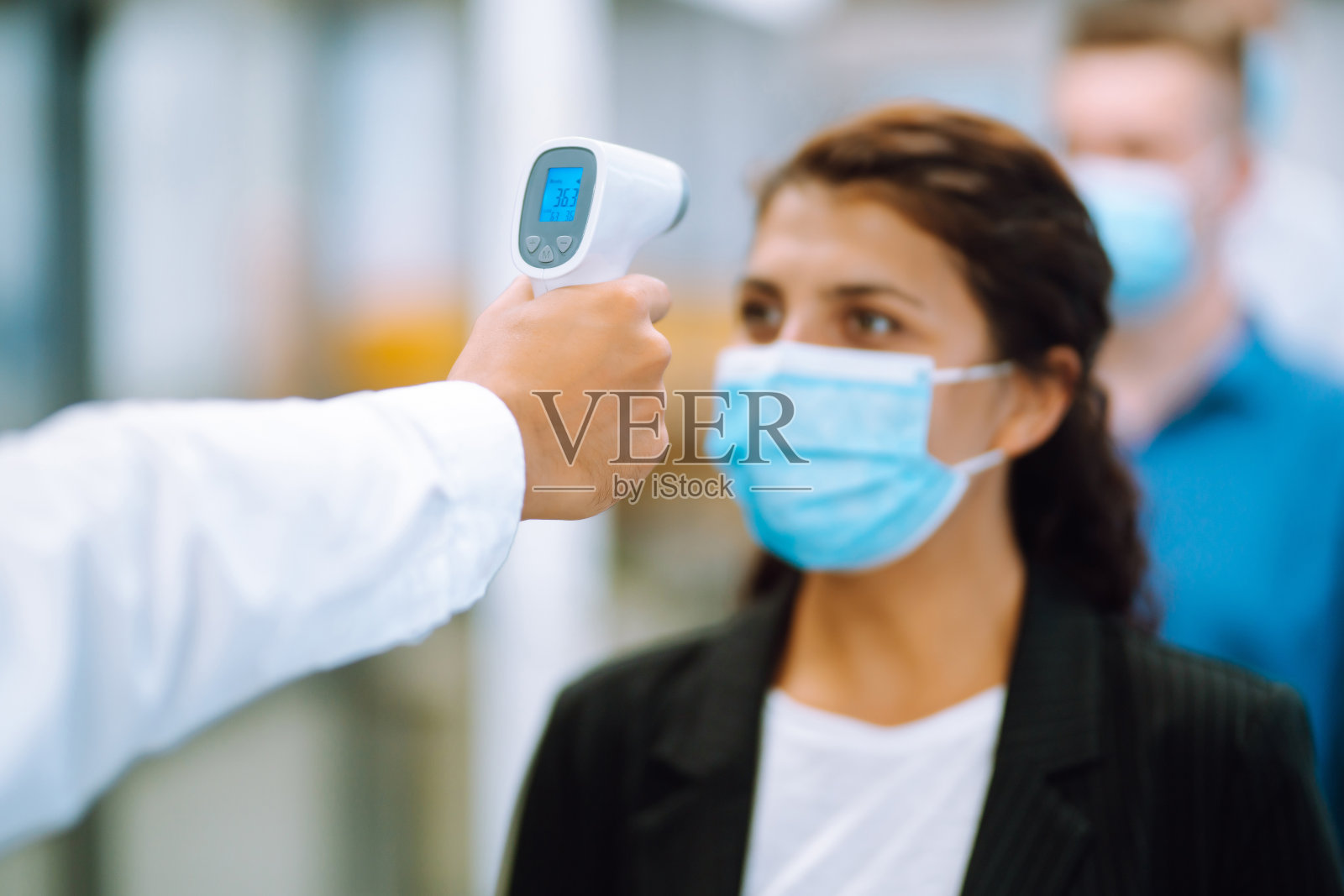 疾病控制专家在进入办公室前使用红外线测温设备检查额头的温度照片摄影图片