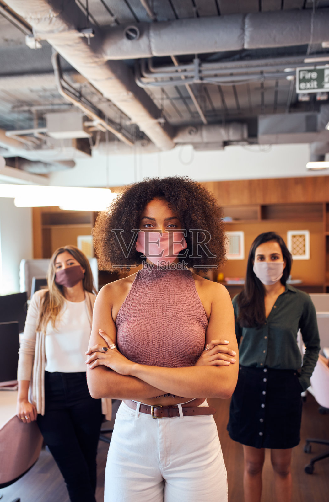 新冠肺炎大流行期间，女性商务团队在开放式办公室戴口罩的情况照片摄影图片