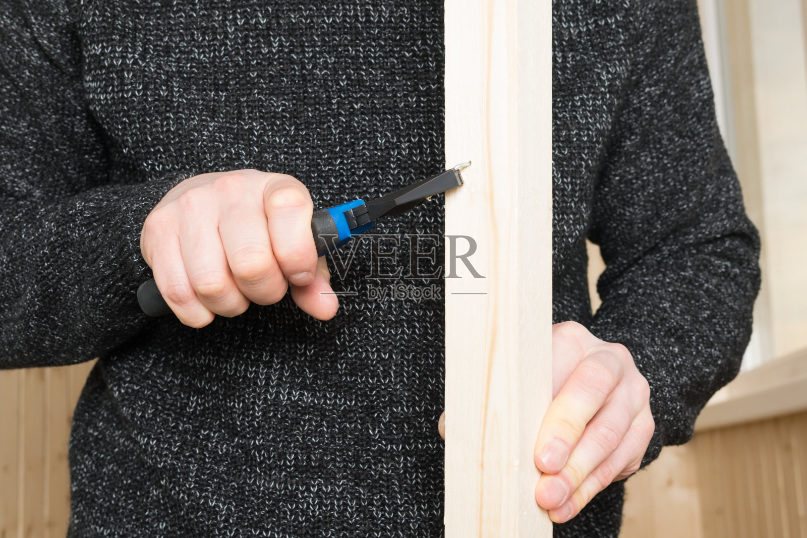 手握木块，用钳子把钉子拔出来，正面照片摄影图片