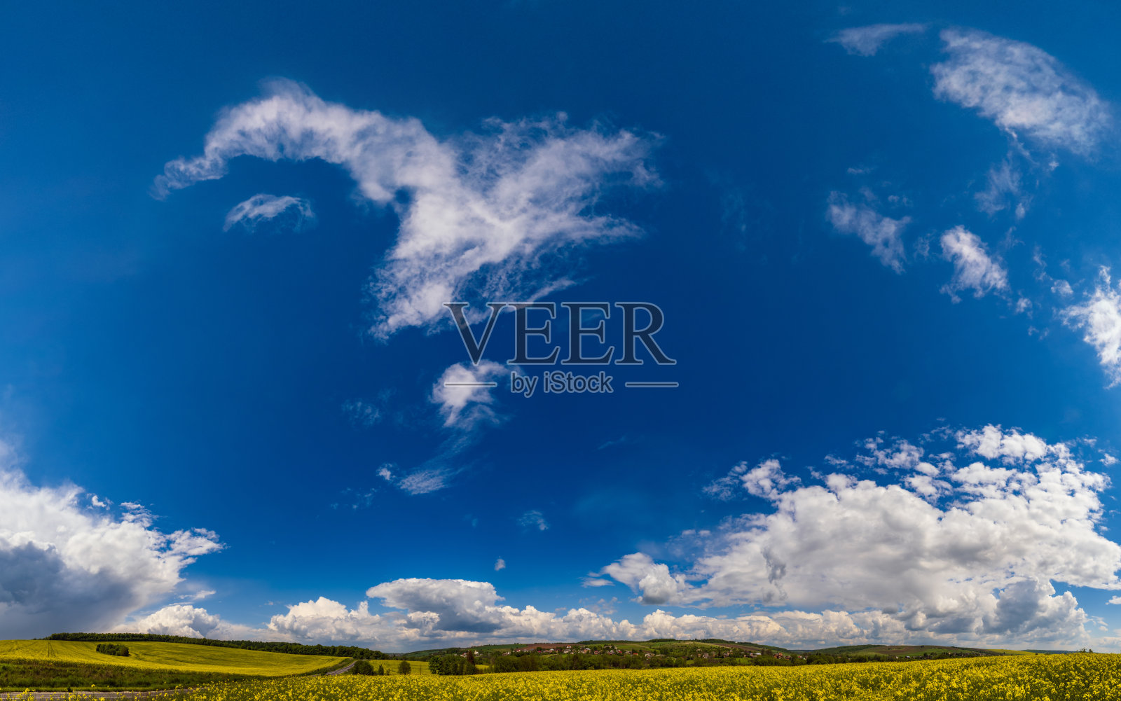 碧蓝的天空和白云笼罩着绿色的乡村和农田。照片摄影图片